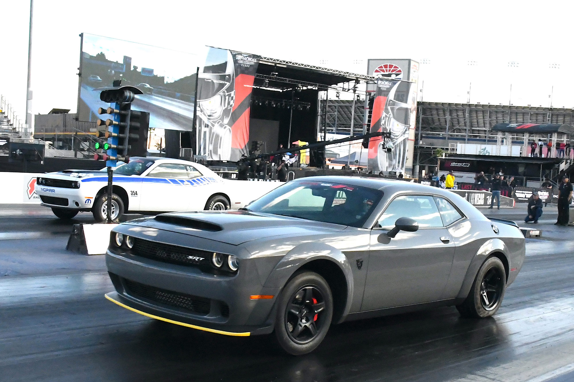 Two Dodge Challengers drag race on a closed track