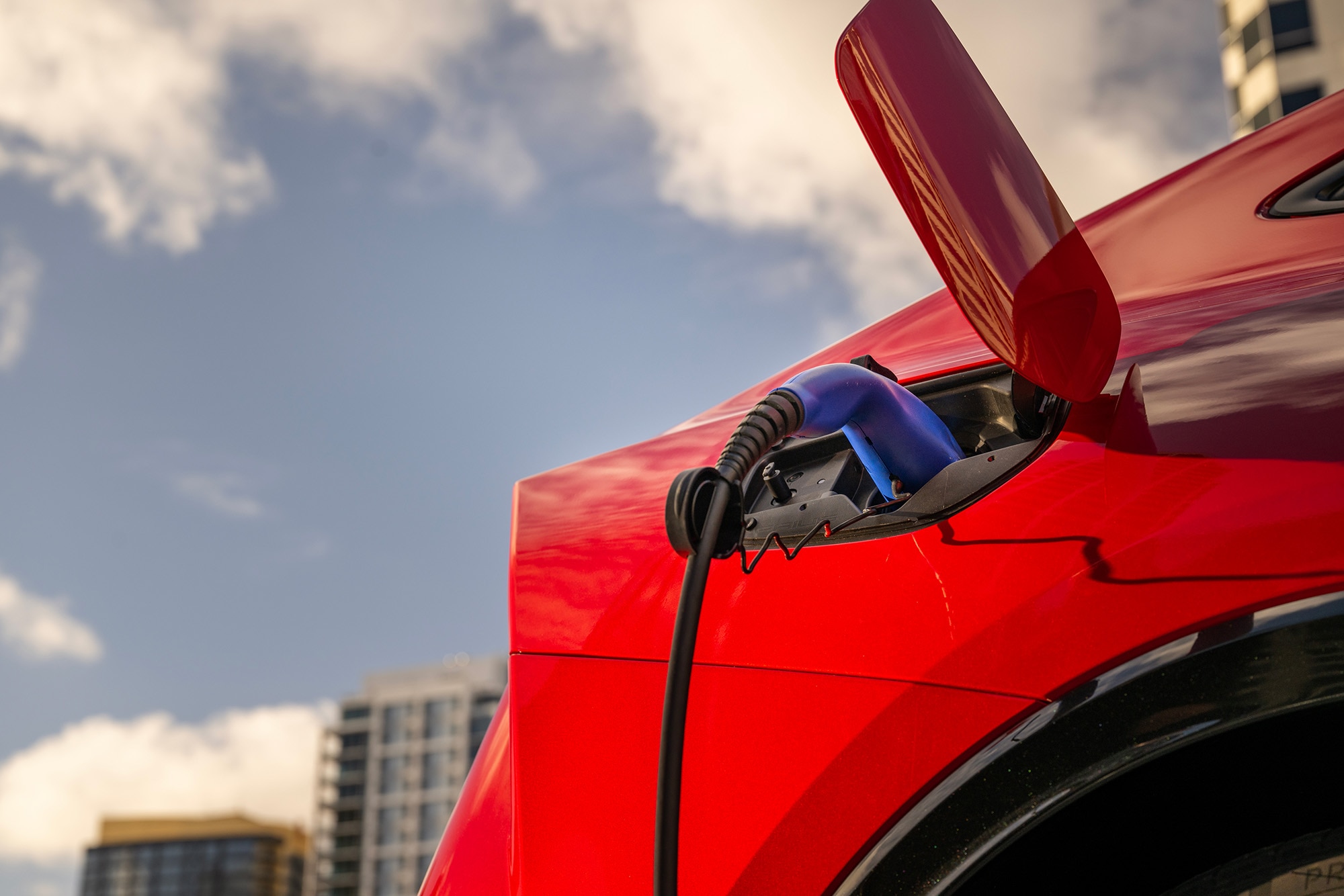 Red Toyota Prius Prime plugged into a charging cable.