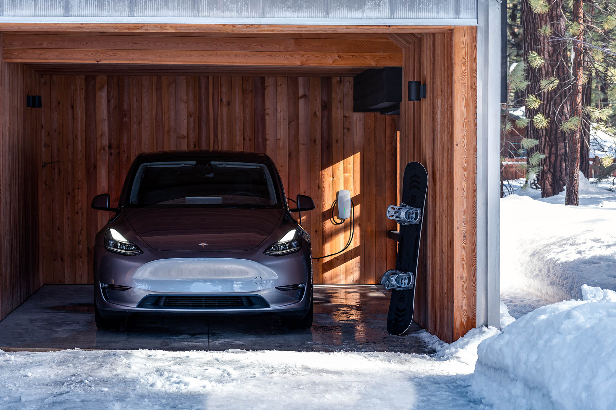 Gray Tesla Model Y parked in a garage on a snowy and icy driveway.