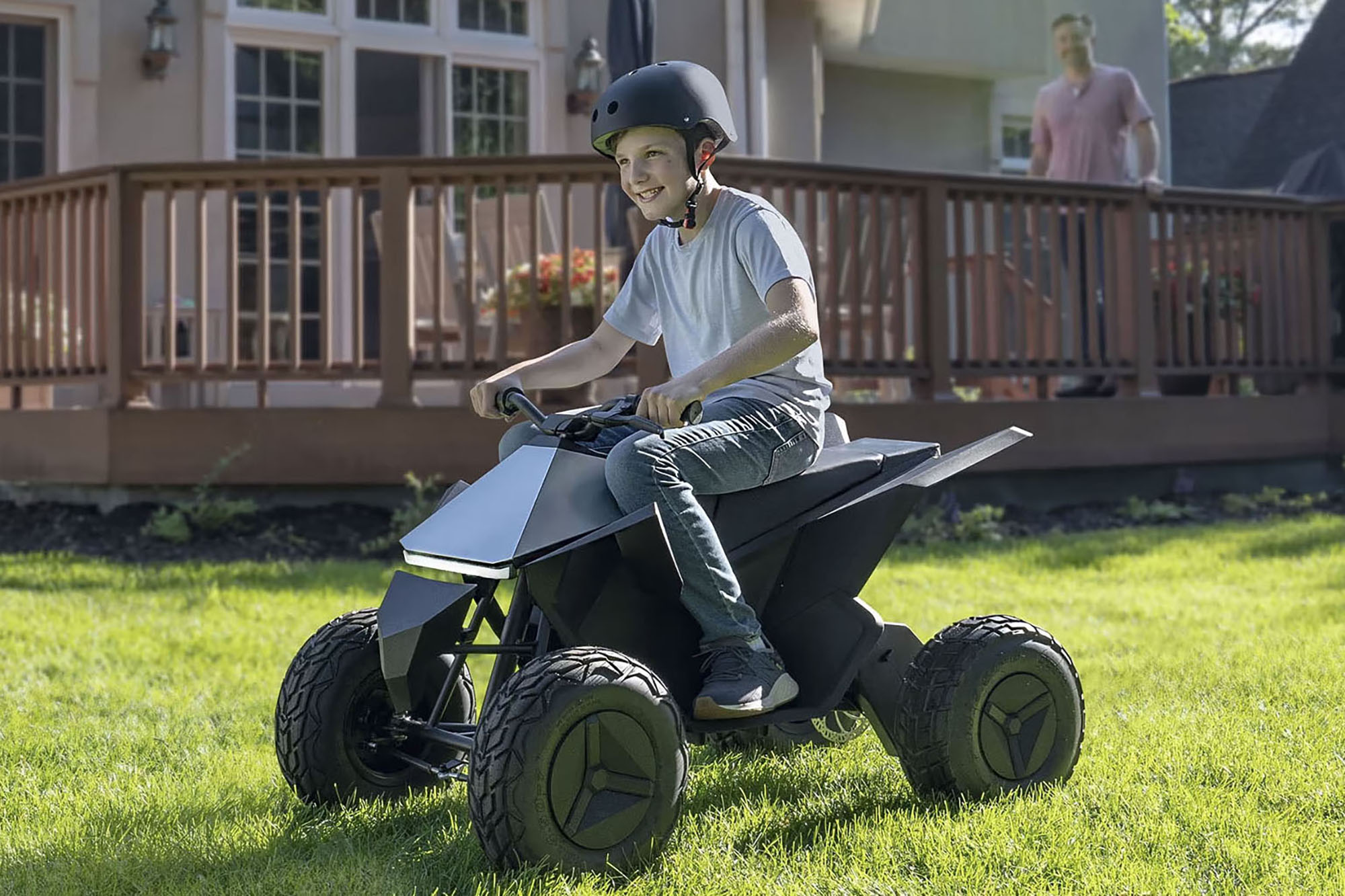 A child riding the Tesla Cyberquad while a parent watches from a deck