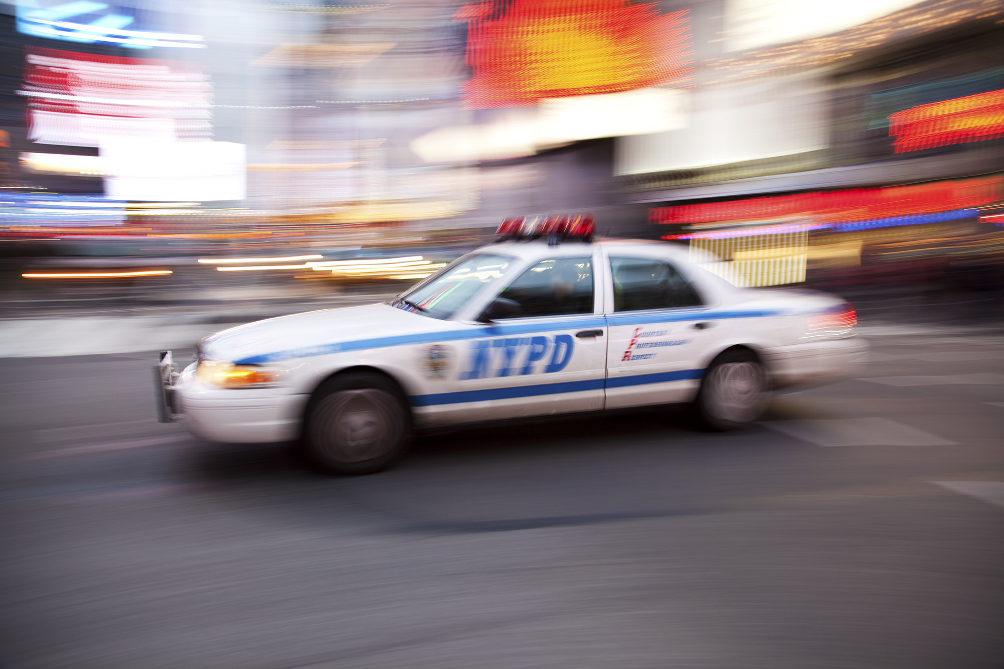 A motion-blurred image of a New York City police car driving