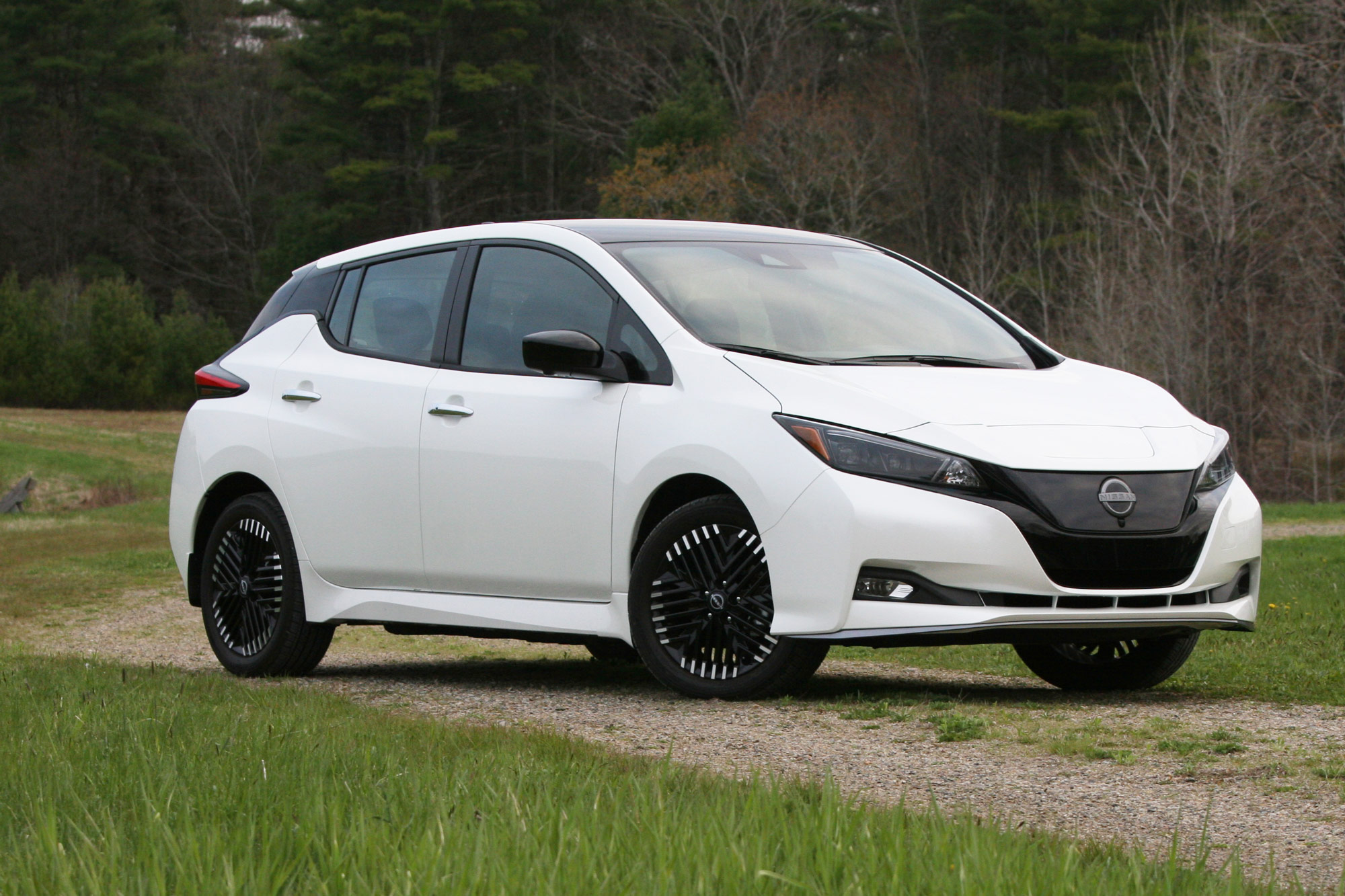 Front-quarter of a white 2024 Nissan Leaf SV Plus parked in a field