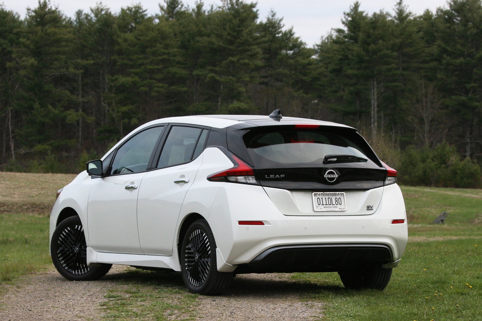 Rear-quarter of a white 2024 Nissan Leaf SV Plus parked in a field