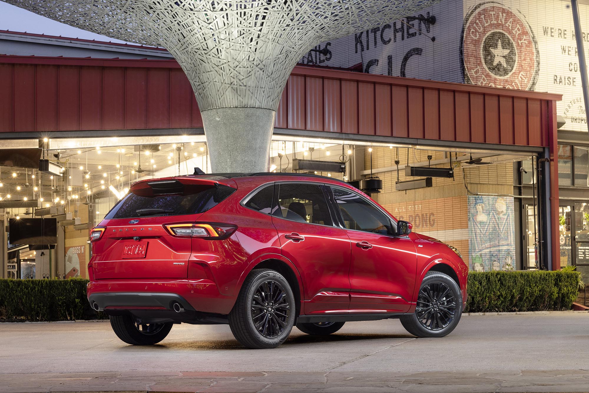 Red Ford Escape parked in front of a retail building.