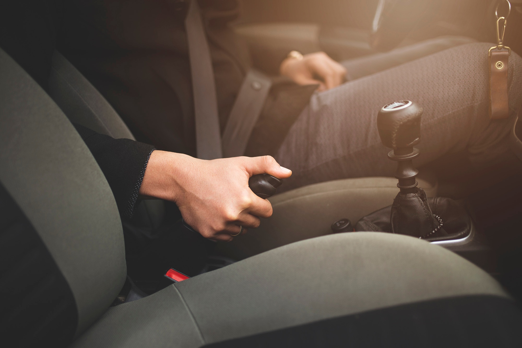 Person's hand operating a parking brake lever inside a car.