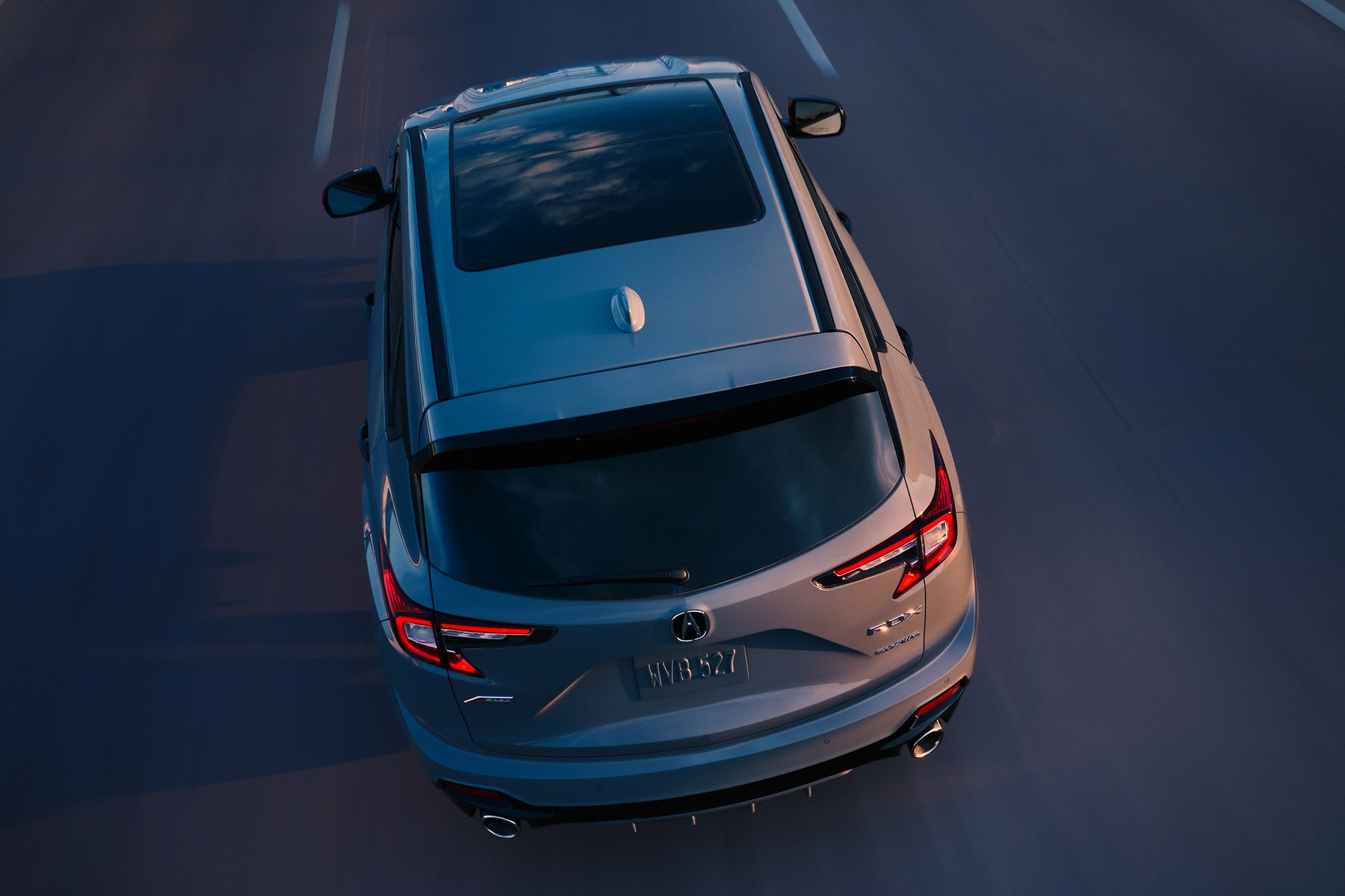 A rear view of a gray 2025 Acura RDX driving on a highway