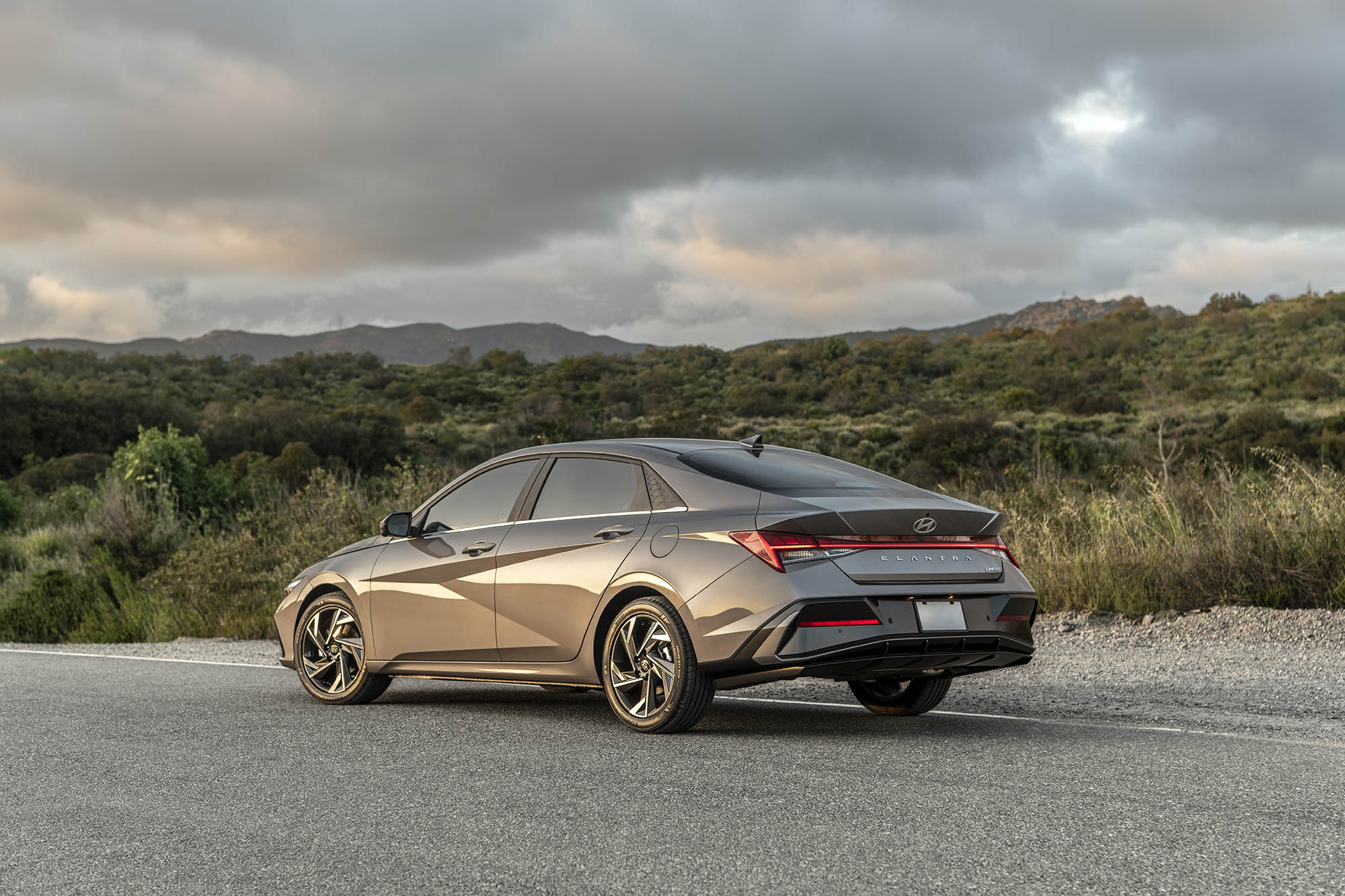 Gray Hyundai Elantra Hybrid parked on pavement next to scrubby terrain