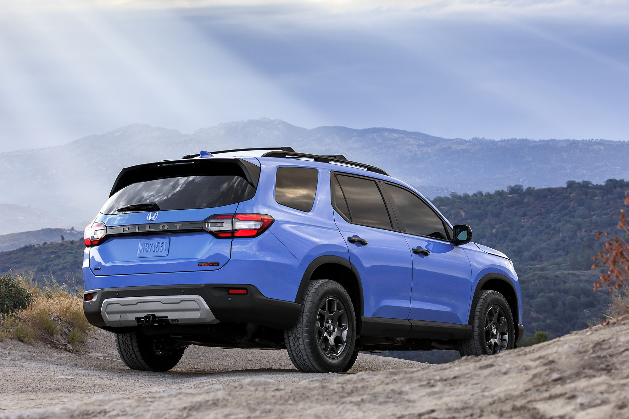 Blue Honda Pilot TrailSport parked on an overlook with mountains in front of it.