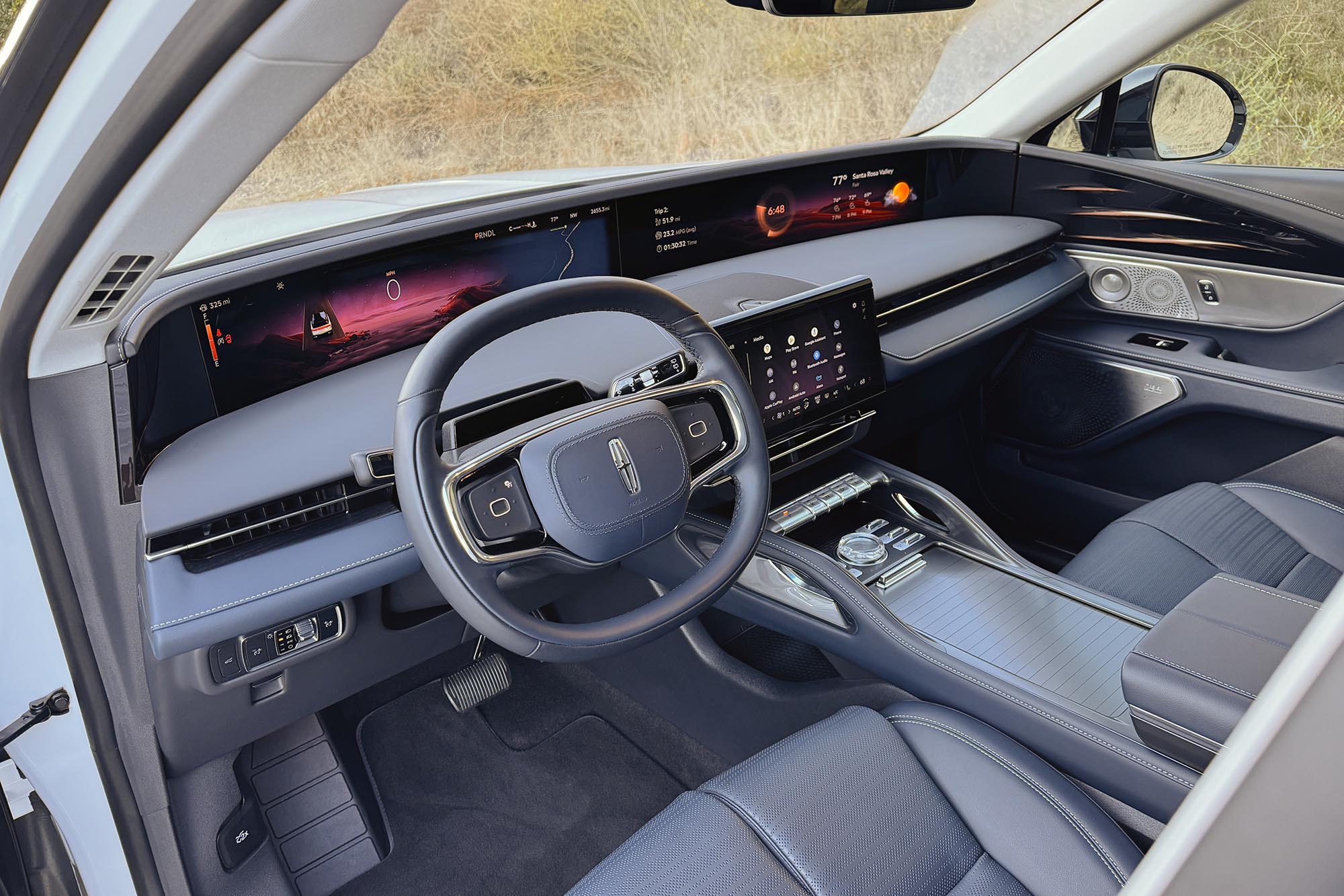 View of a 2024 Lincoln Nautilus interior showing the panoramic display screen, dashboard, center console, and blue leather front seats.