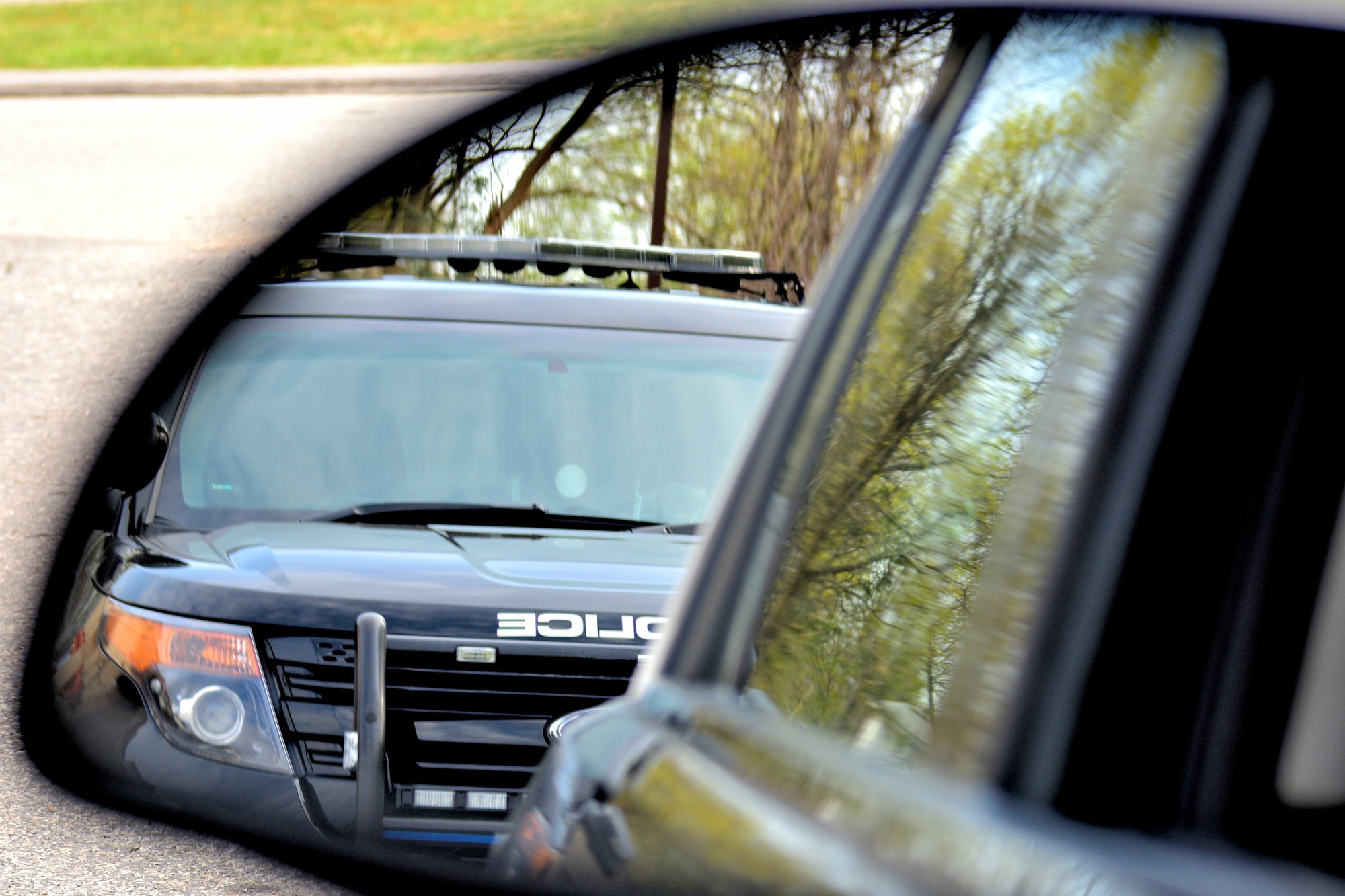 Police car pulling over a motorist in the driver's side mirror