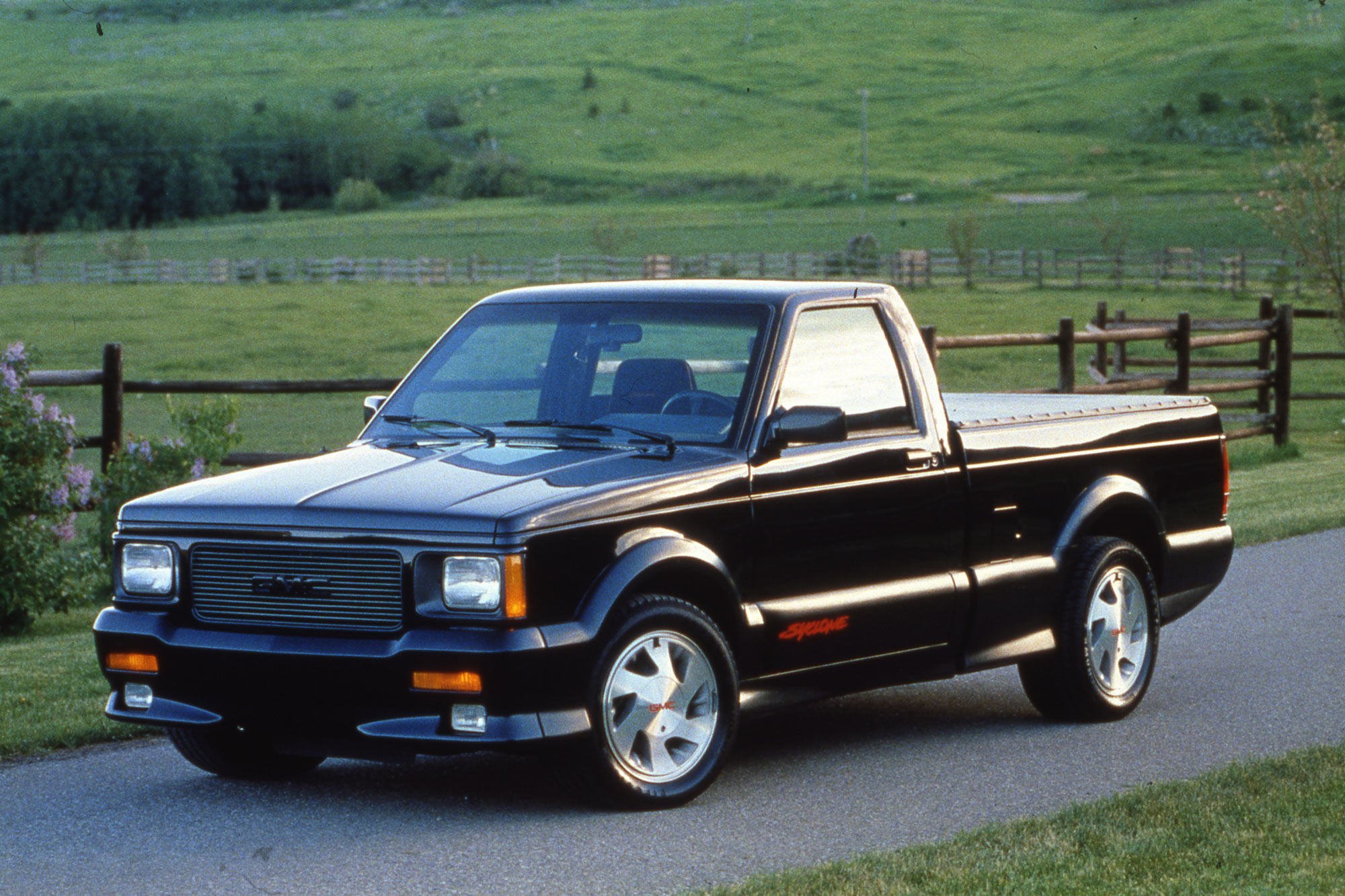 1991 GMC Syclone parked on pavement by a pasture.