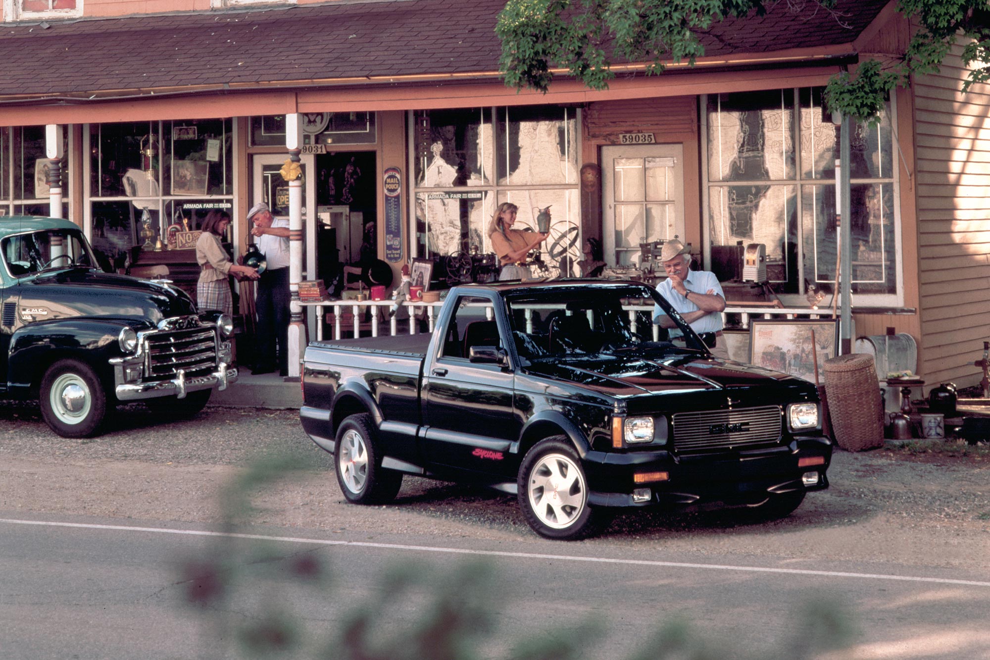 1991 GMC Syclone parked in front of a shop, being admired.