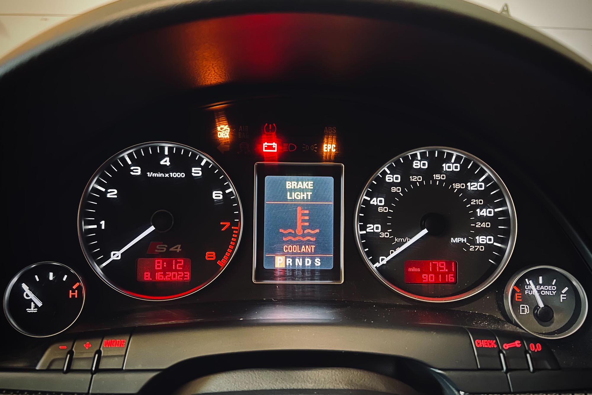 Driver's instrument cluster in vehicle with coolant warning illuminated.