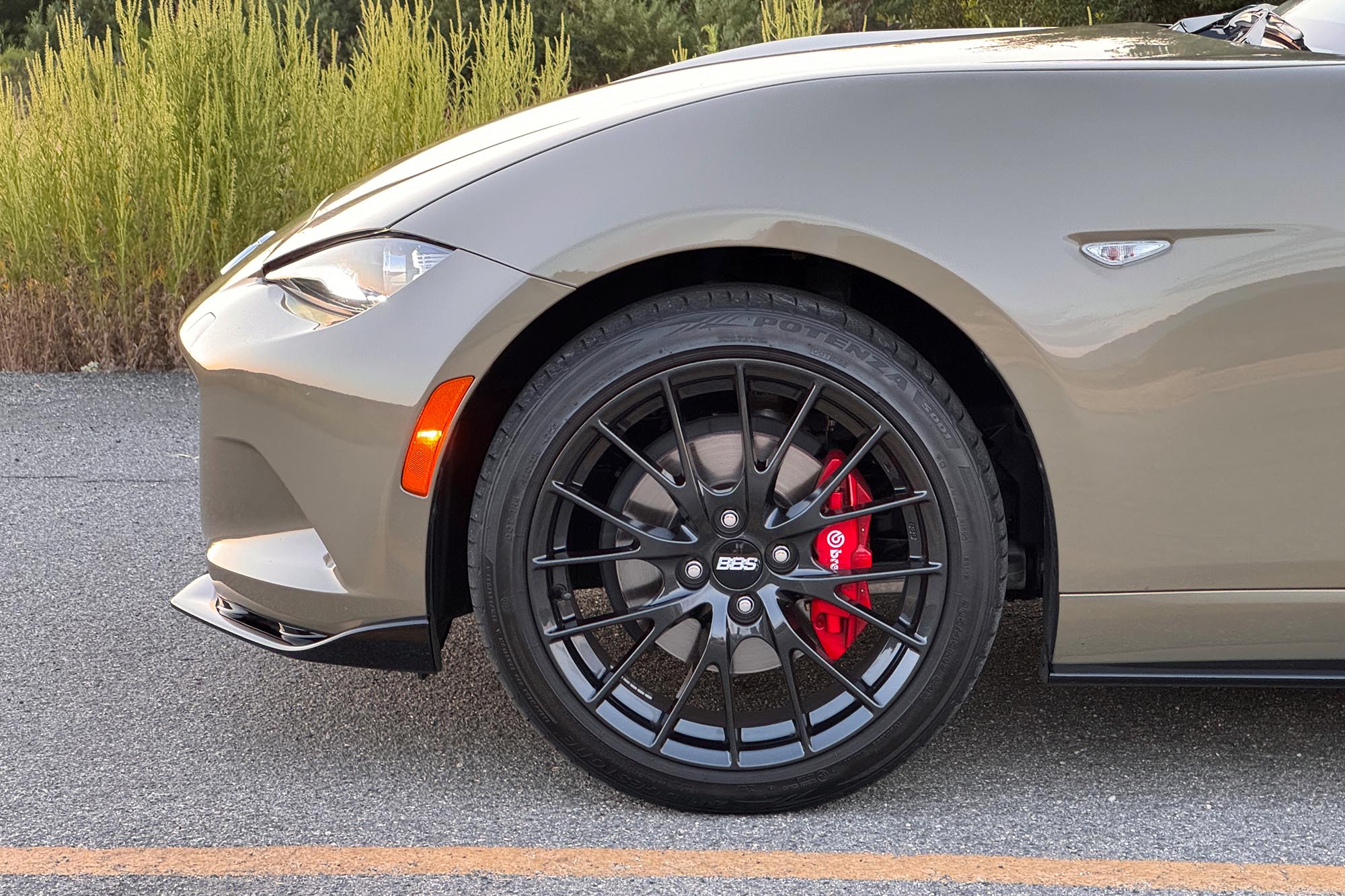 View of a 2024 Mazda MX-5 Miata RF Club showing the BBS forged aluminum front wheel, Brembo brakes with red calipers, and Appearance package's lower body kit.