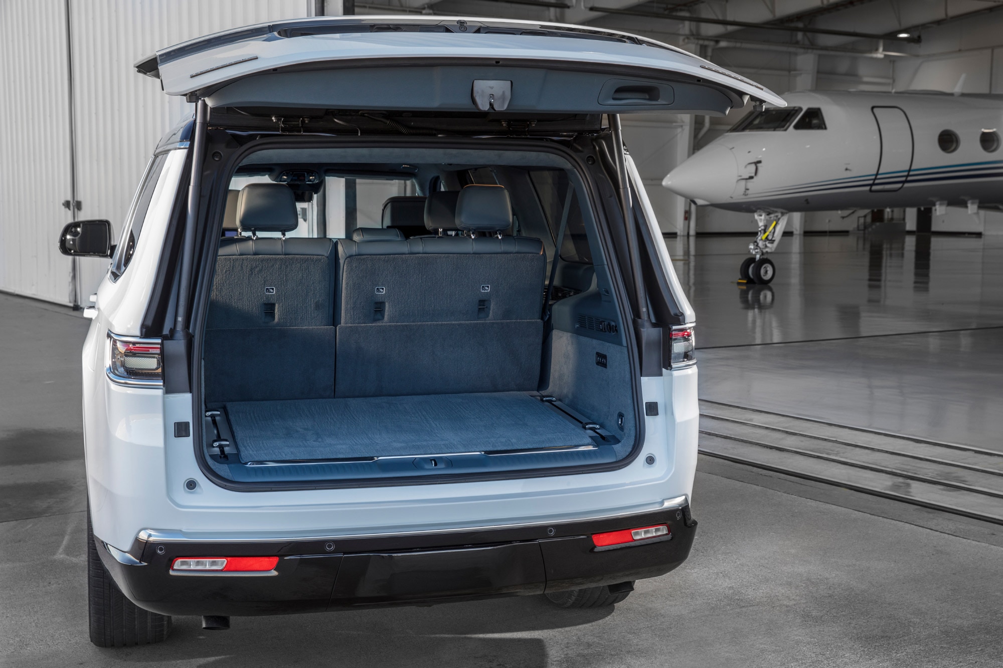 2024 Jeep Grand Wagoneer with liftgate open by airplane hangar.