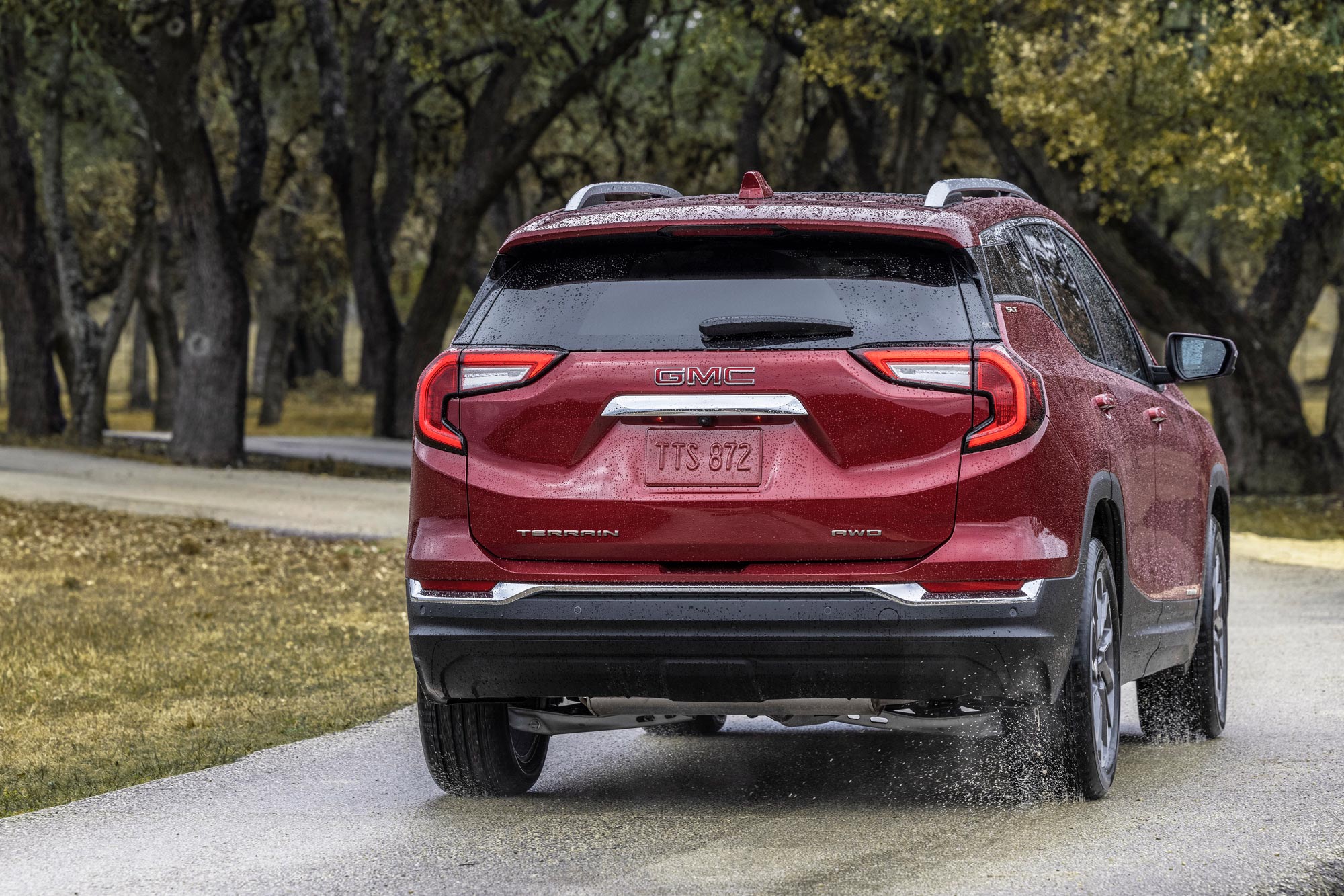 Rear view of 2024 GMC Terrain driving on wet road.