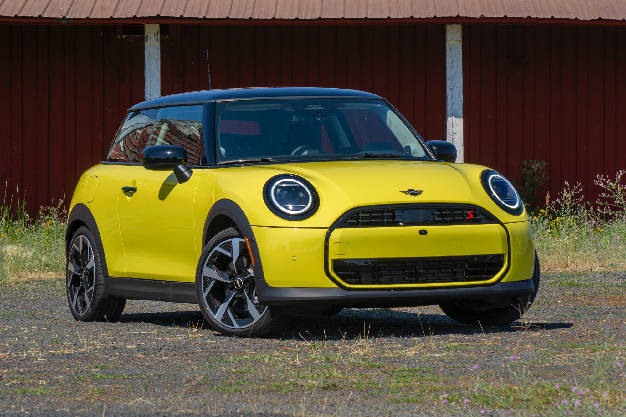 Yellow 2025 Mini Cooper parked on gravel.