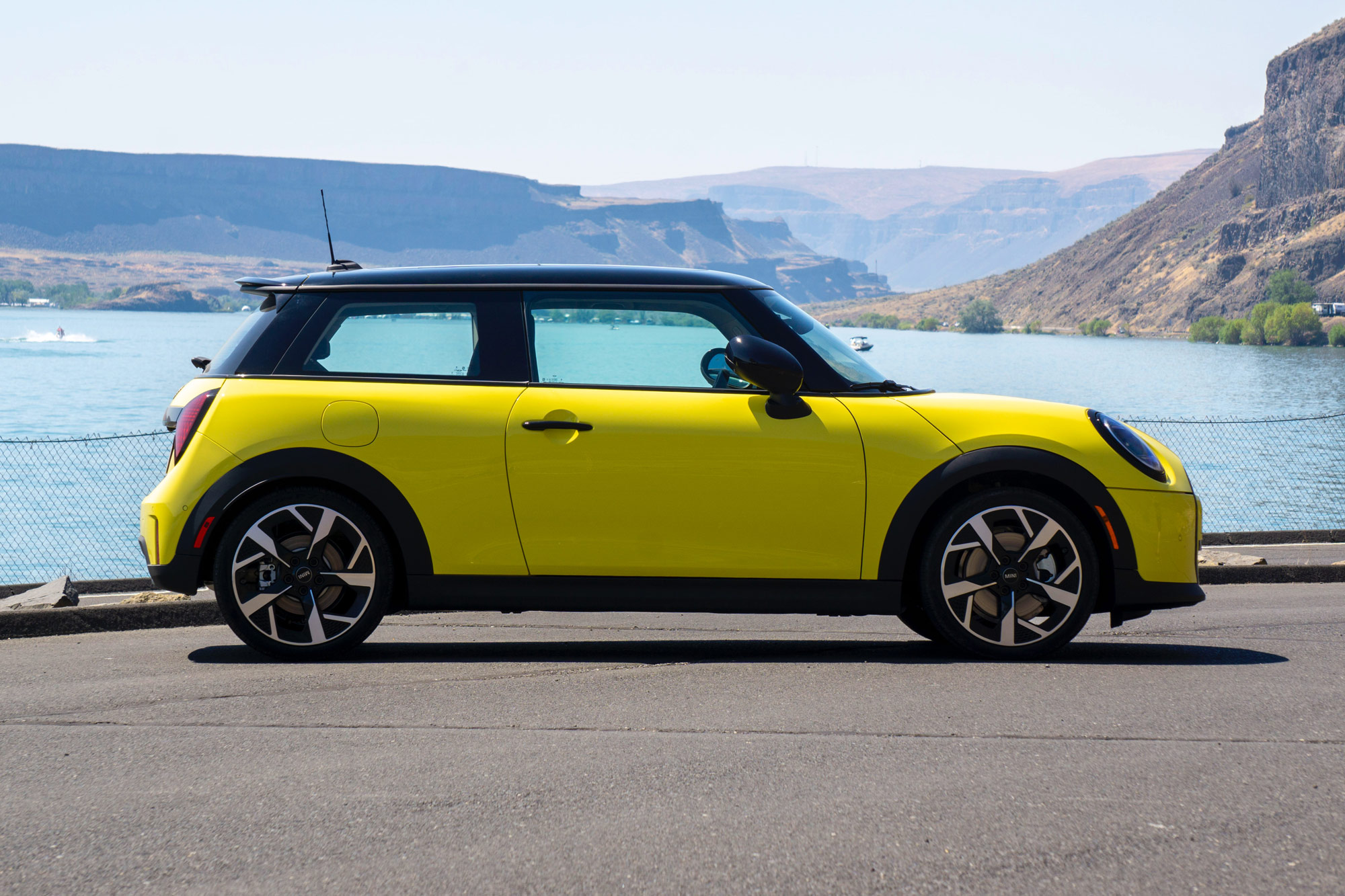 Yellow 2025 Mini Cooper parked by a river.