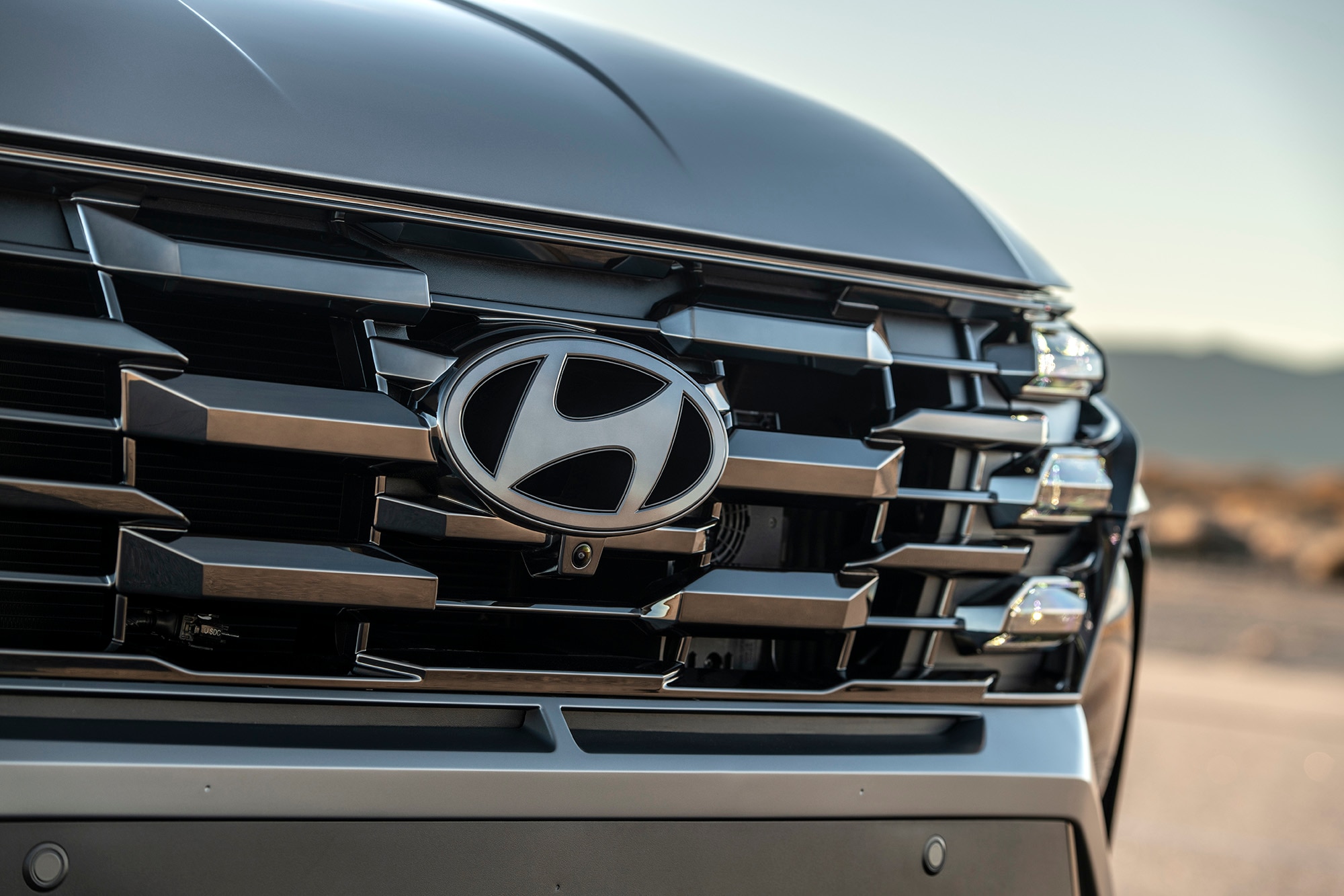 The grille and badge of a Hyundai Santa Fe Plug-In Hybrid vehicle in dark silver.