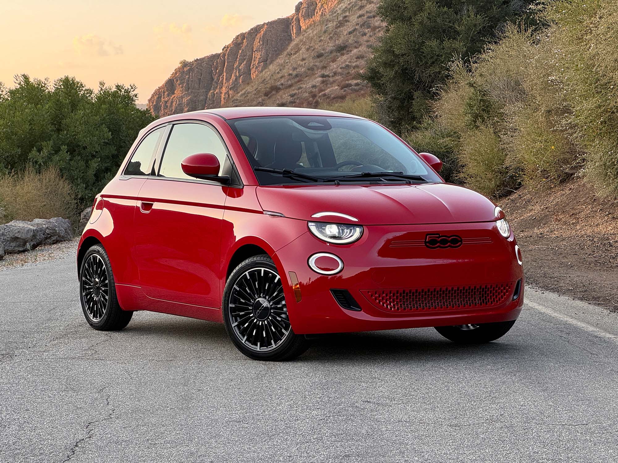 2024 Fiat 500e in red parked on a road at sunset