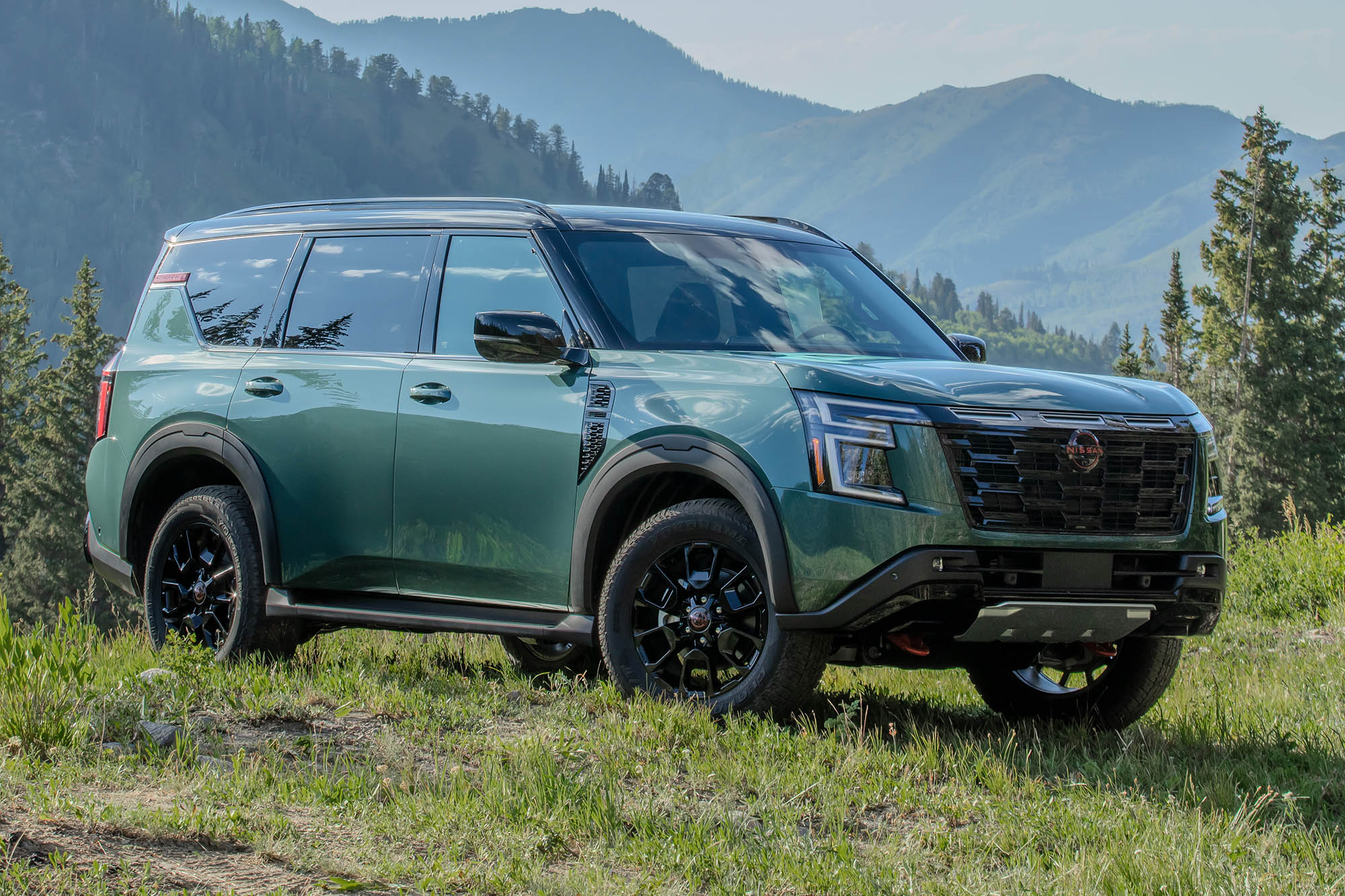 A right-front view of a green 2025 Nissan Armada in front of mountains.