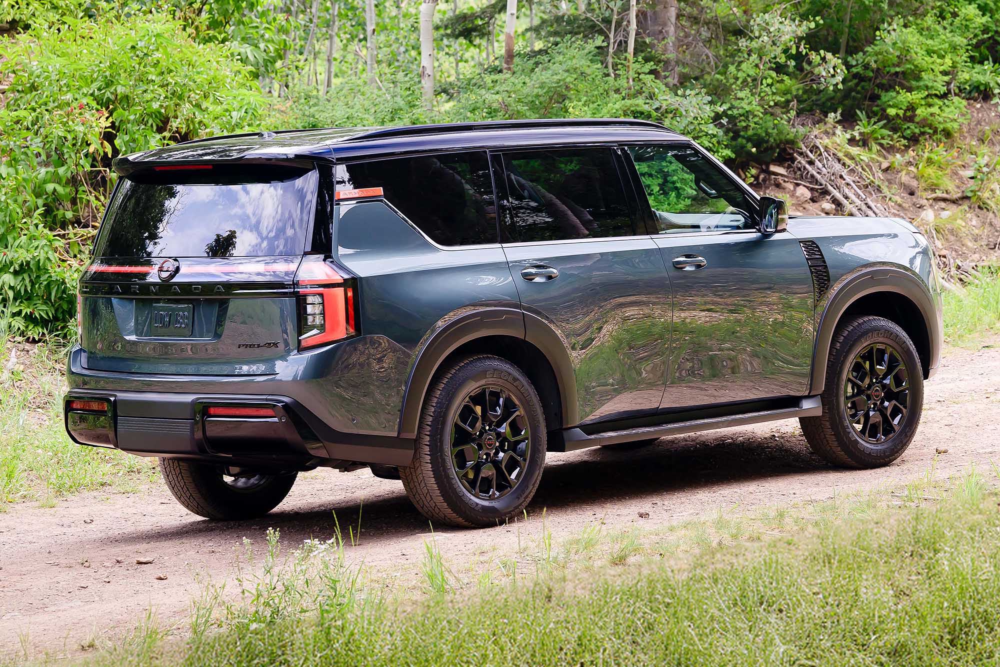 A right-rear view of a green 2025 Nissan Armada on a trail.