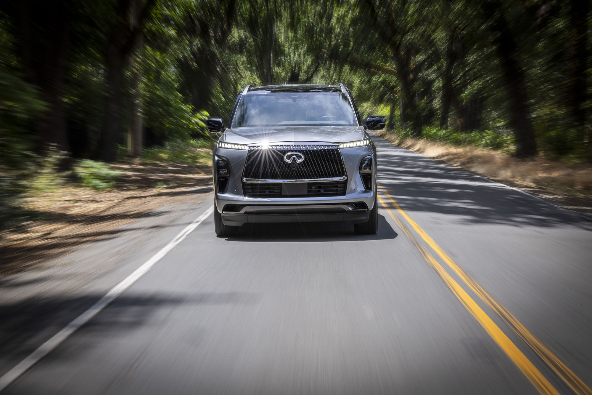 Front view of a 2025 Infiniti QX80 driving down a paved road.