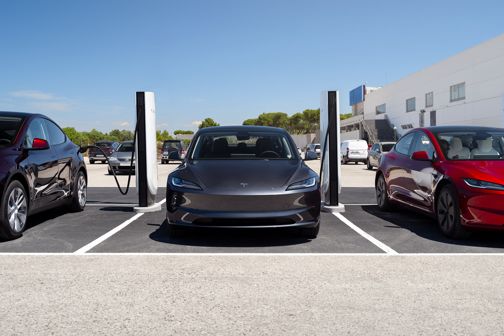 Three Tesla vehicles hooked up to Tesla charging stations.