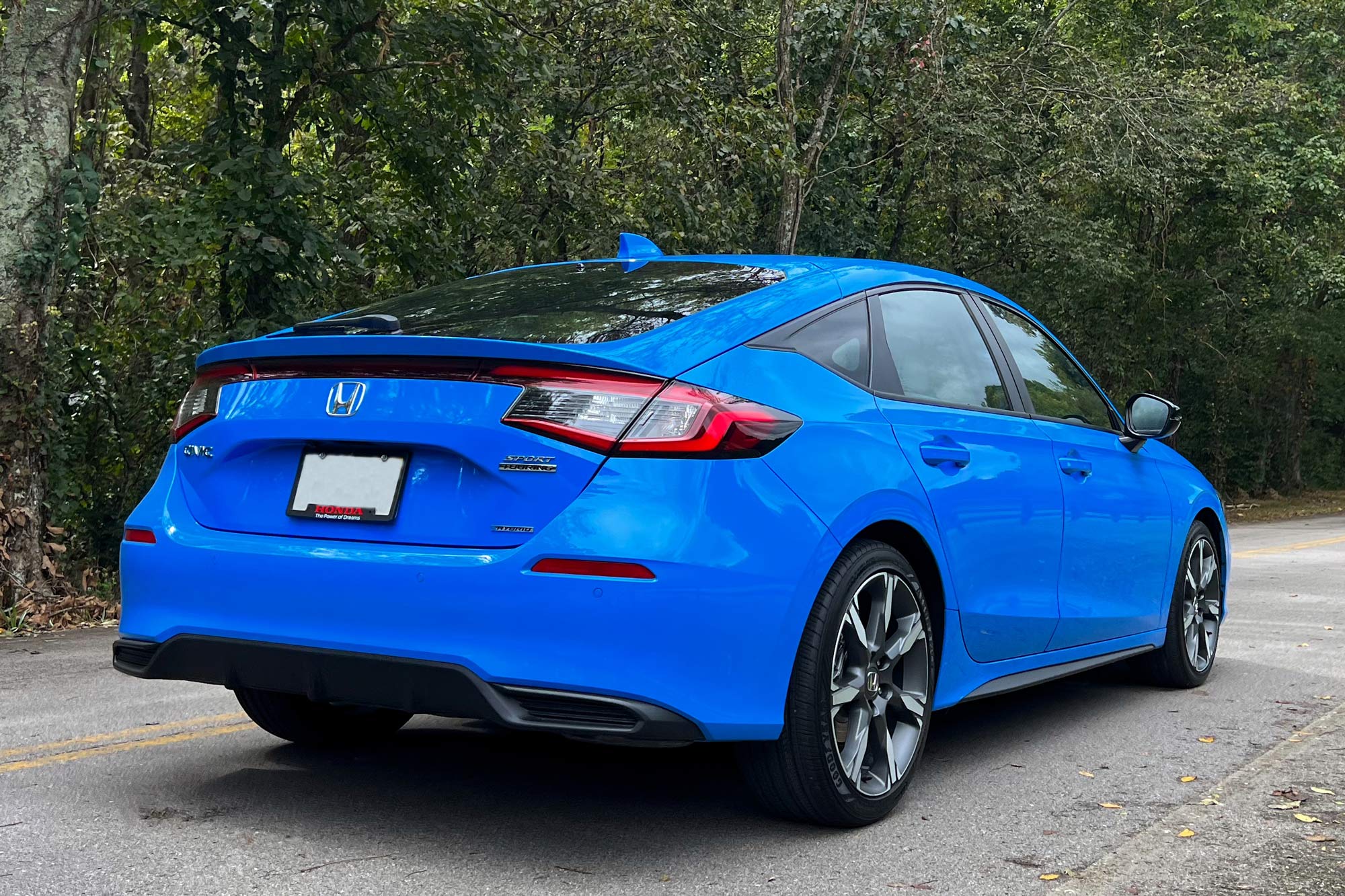 Rear of a 2025 Honda Civic Sport Touring Hybrid hatchback in Boost Blue