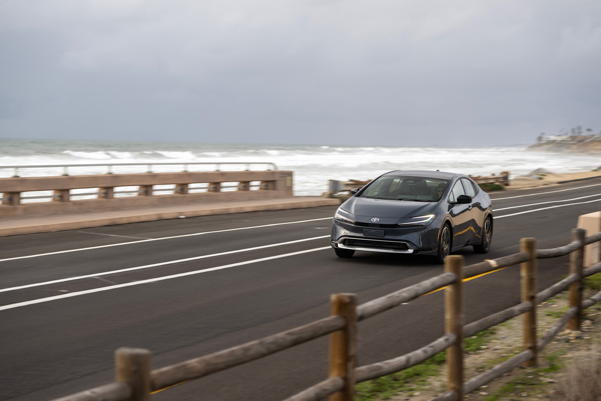 2024 Toyota Prius driving on seaside road.