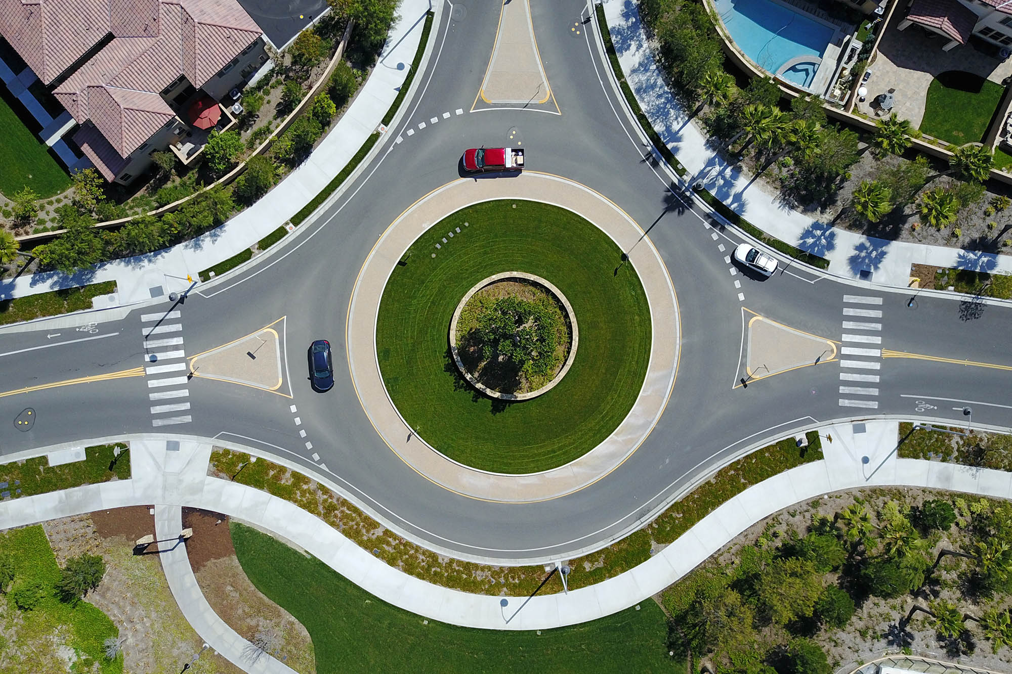 Aerial view of a roundabout with three cars in it.