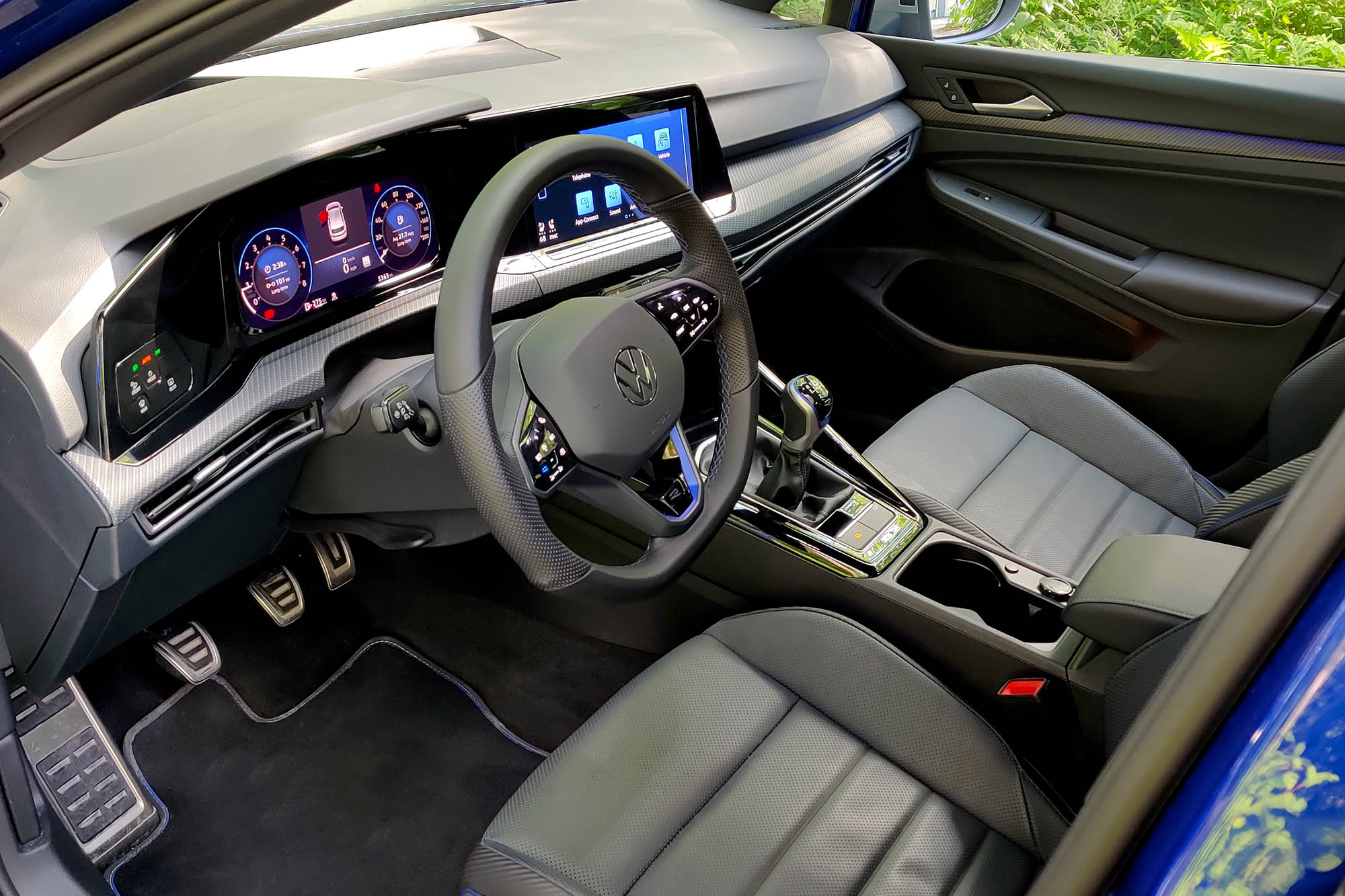 View of a 2024 Volkswagen Golf R interior showing the dashboard, front seats, and manual transmission.