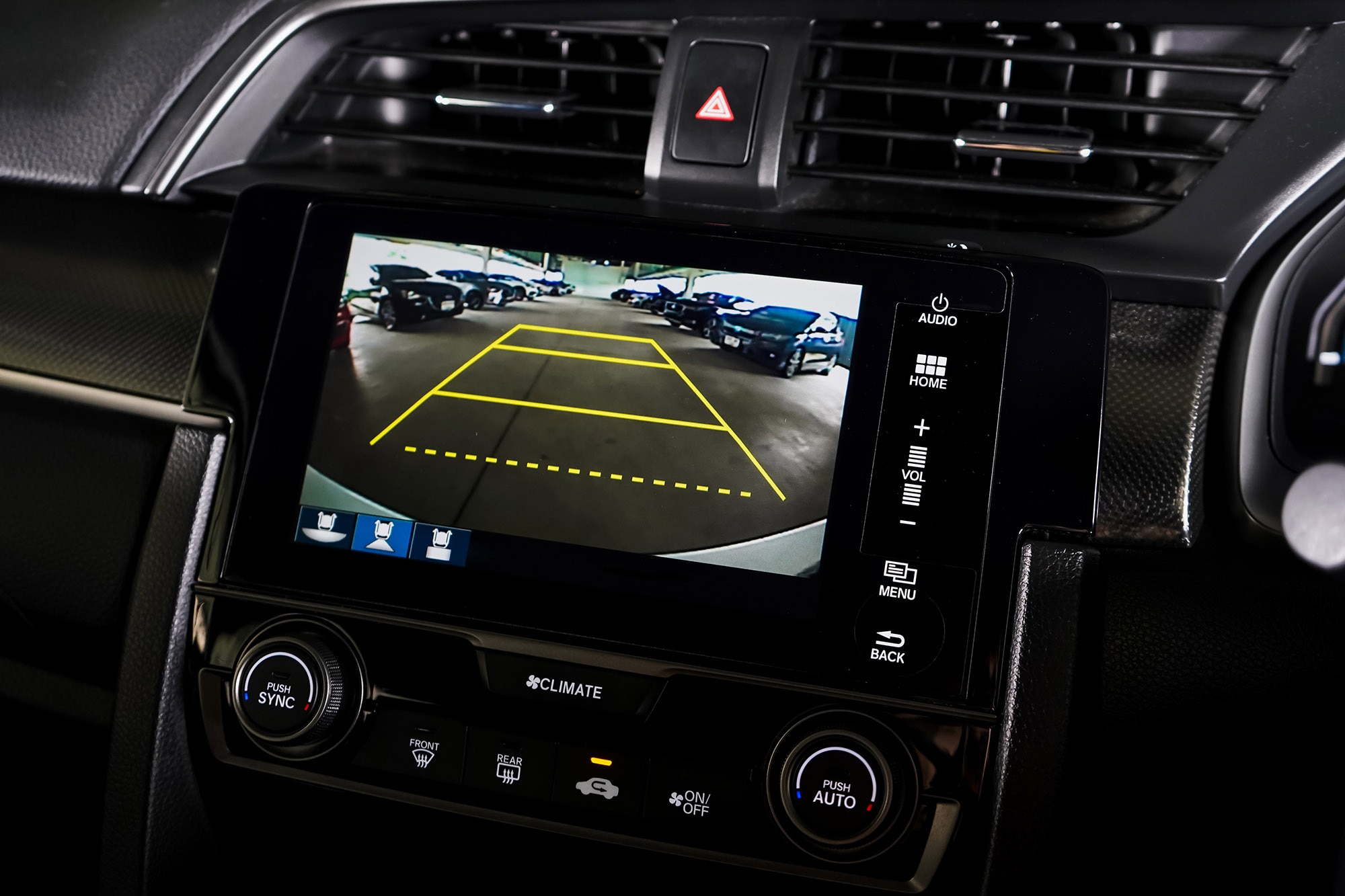 Rearview camera in a vehicle's infotainment screen, showing the reverse path of the vehicle in yellow lines.