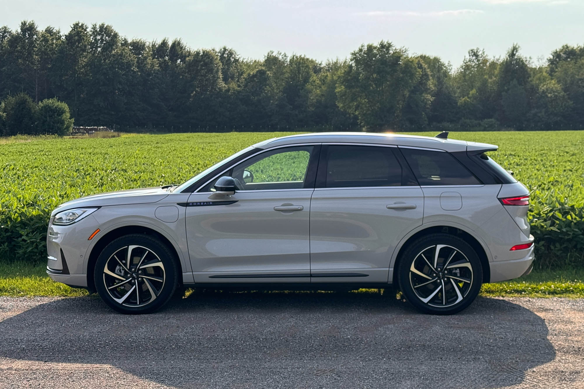 2024 Lincoln Corsair Grand Touring in Ceramic parked on a dirt road with a field and trees in the background.