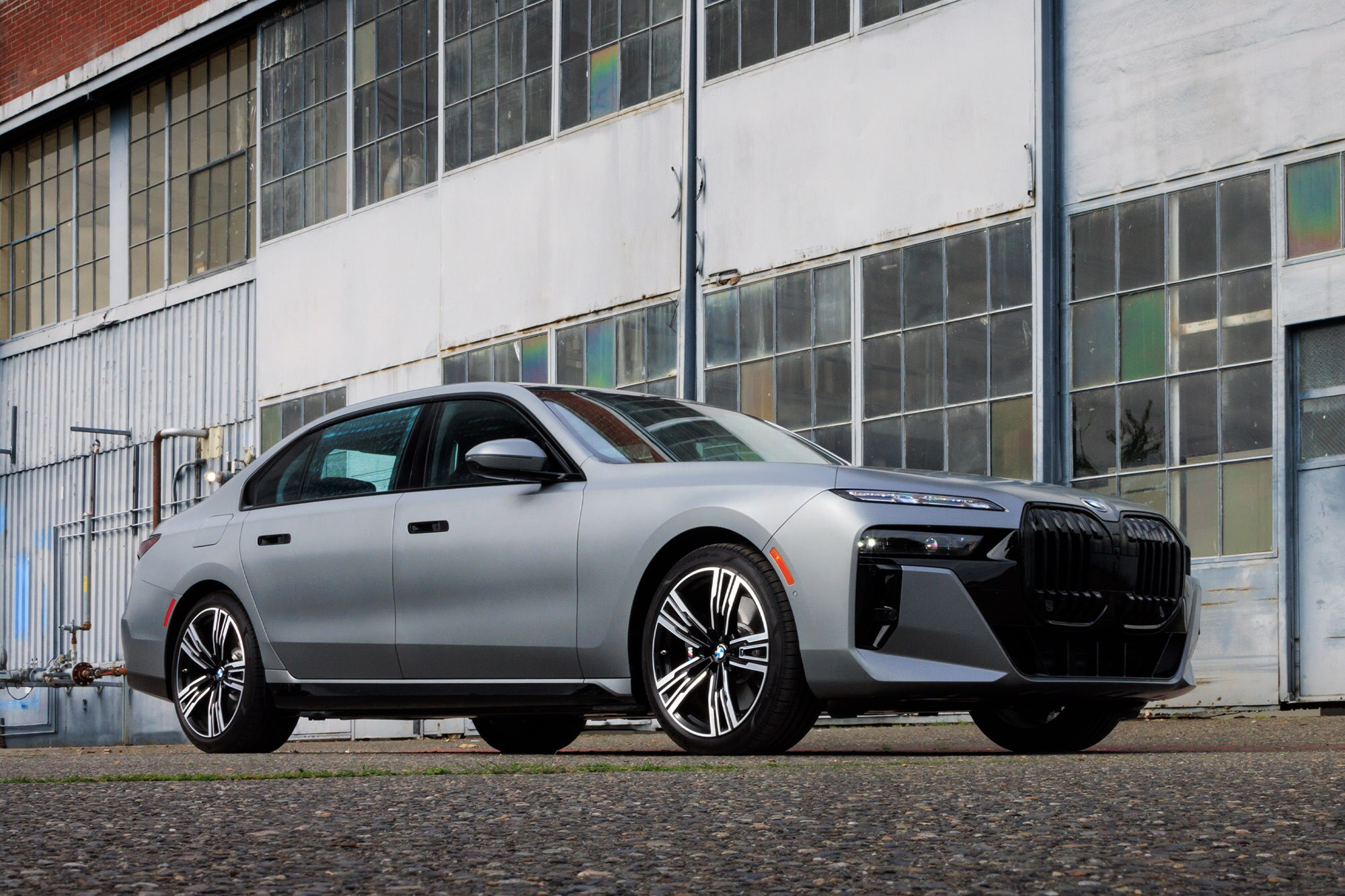 2024 BMW 750e plug-in hybrid in Frozen Pure Grey Metallic parked in front of an industrial building