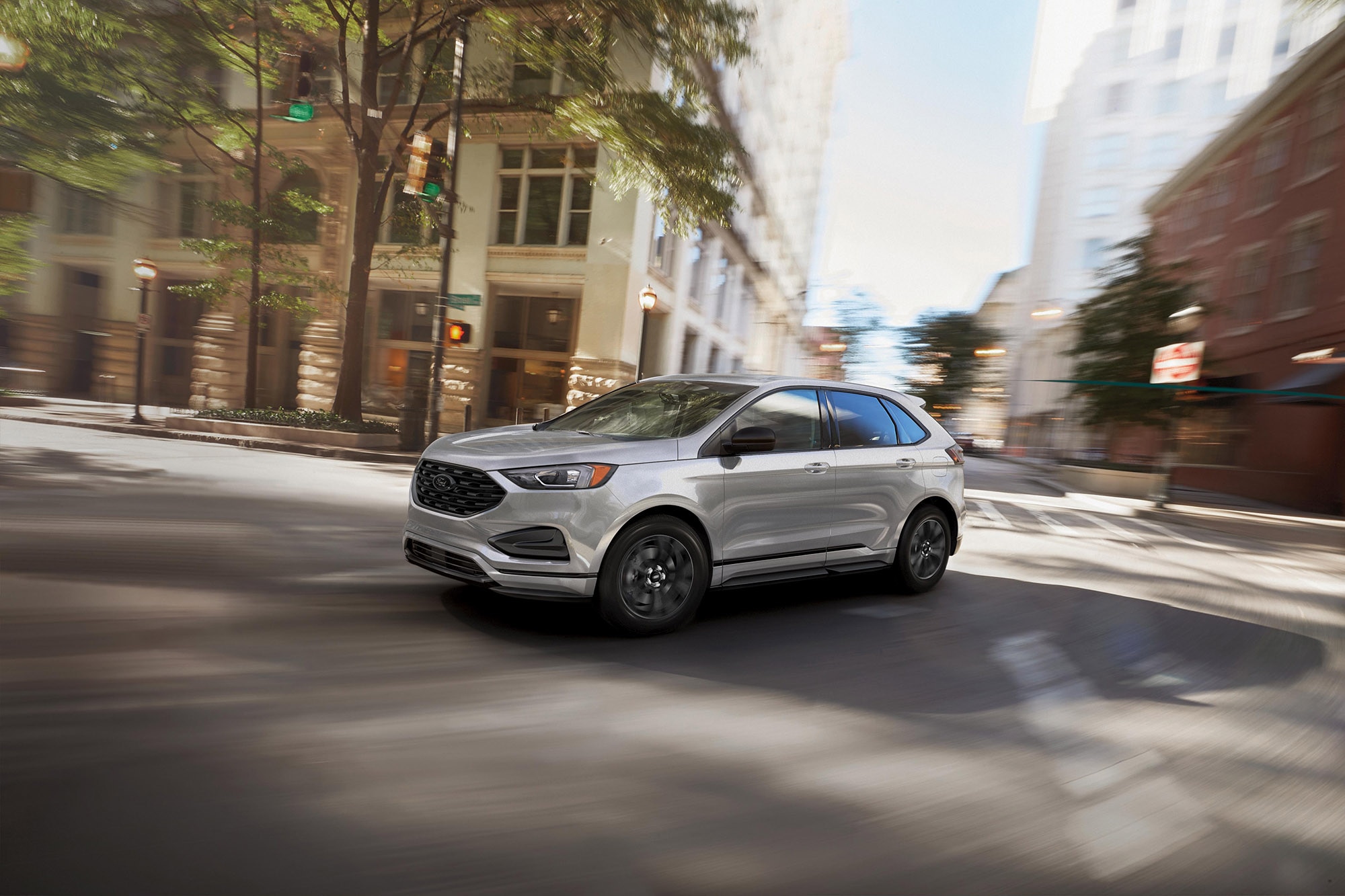 A silver Ford Edge driving in an urban environment.