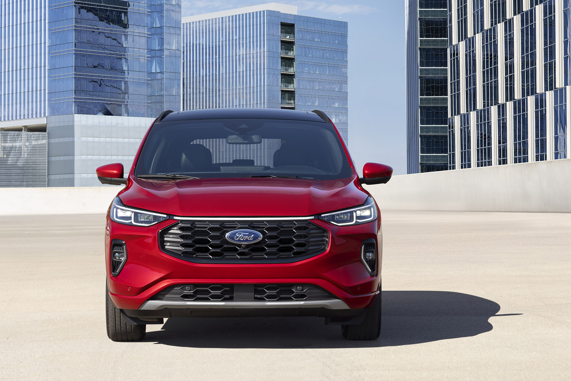 A red Ford Escape facing the camera with tall buildings behind.