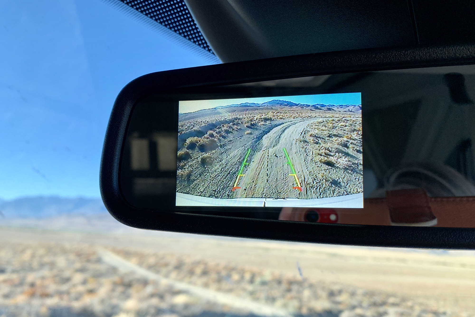 Vehicle rearview mirror with a camera image inset.