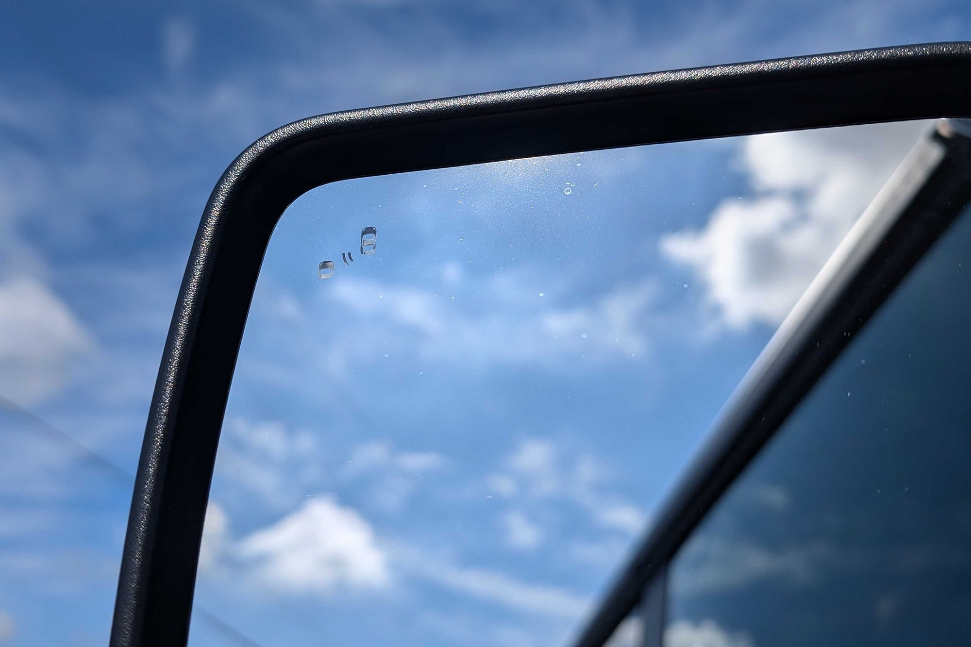 Indicator sign for someone in the blind spot in a car's driver-side mirror.