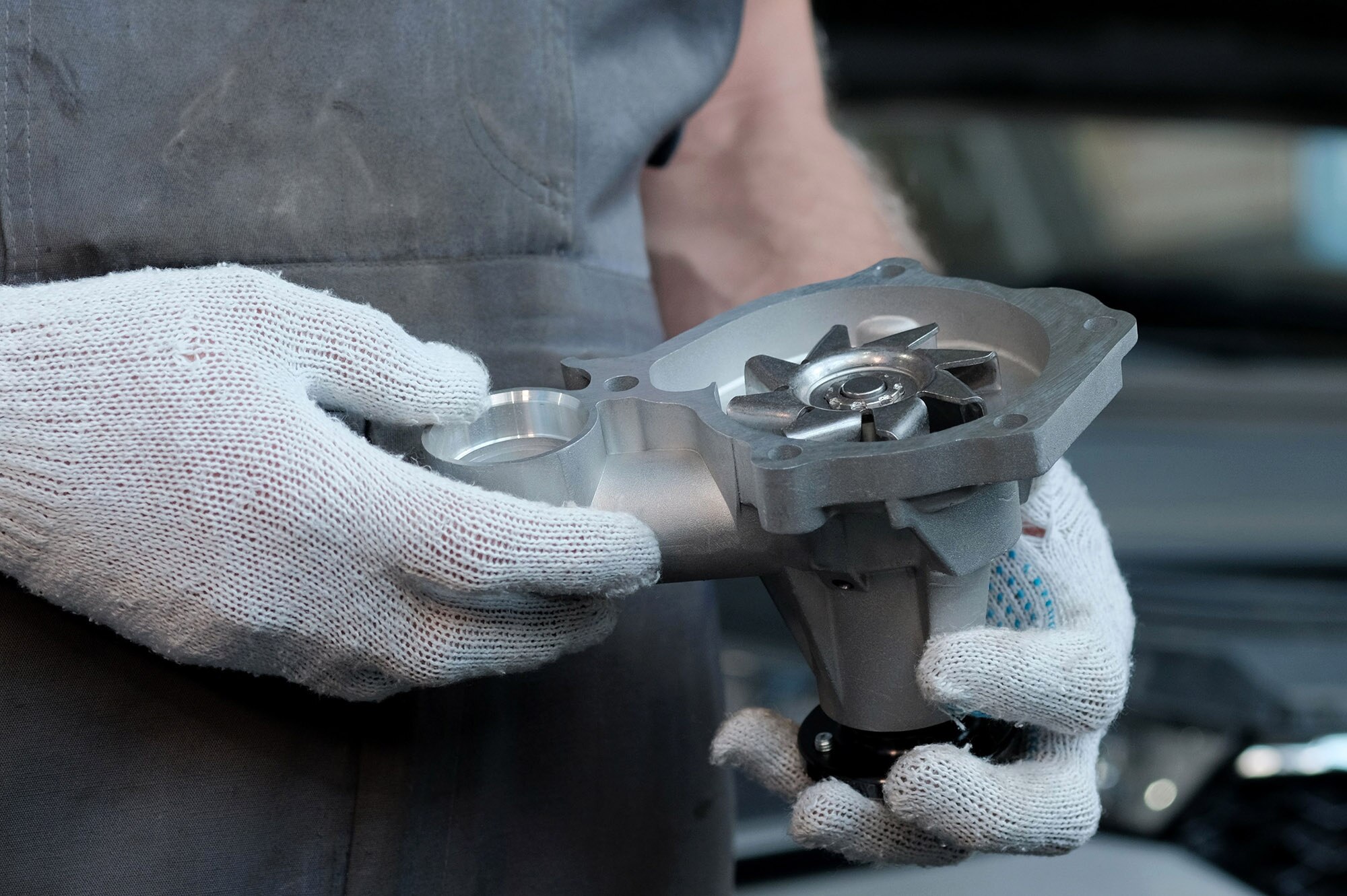 Persons gloved hands holding a water pump for a vehicle