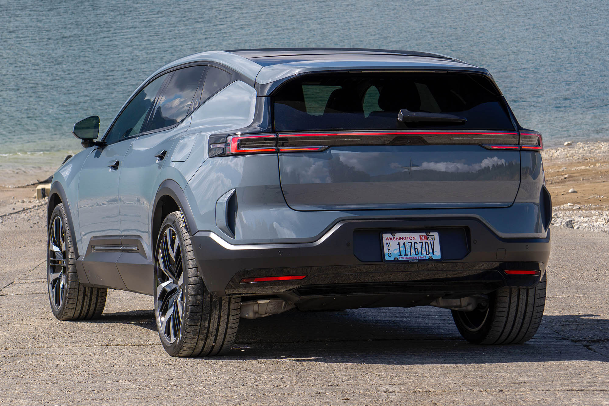 Left-rear view of a gray 2025 Polestar 3 Launch Edition with a lake in the background.