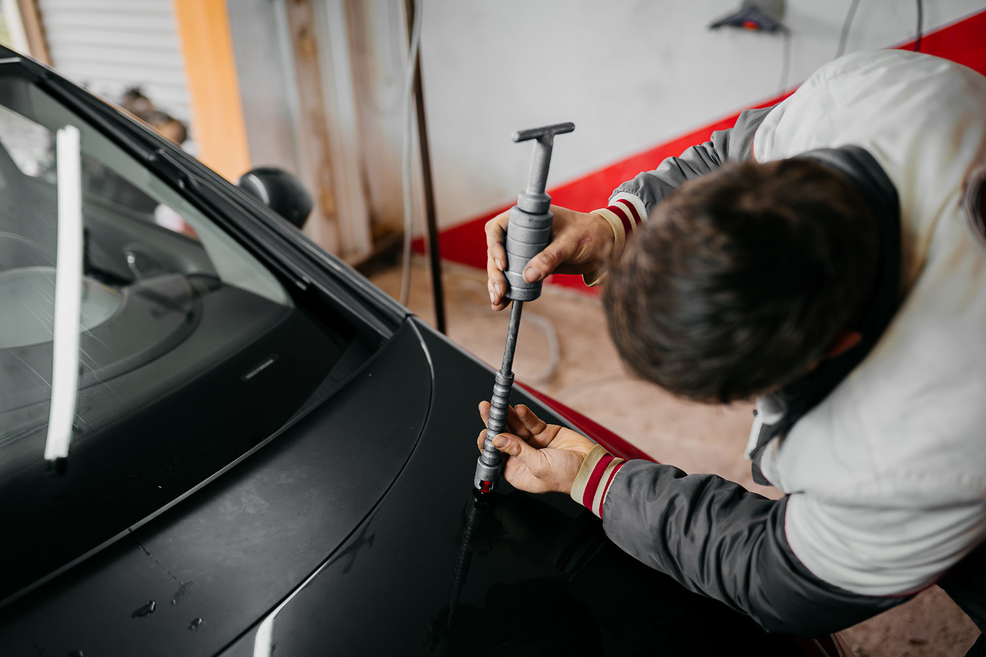 A technician performing a paintless dent repair