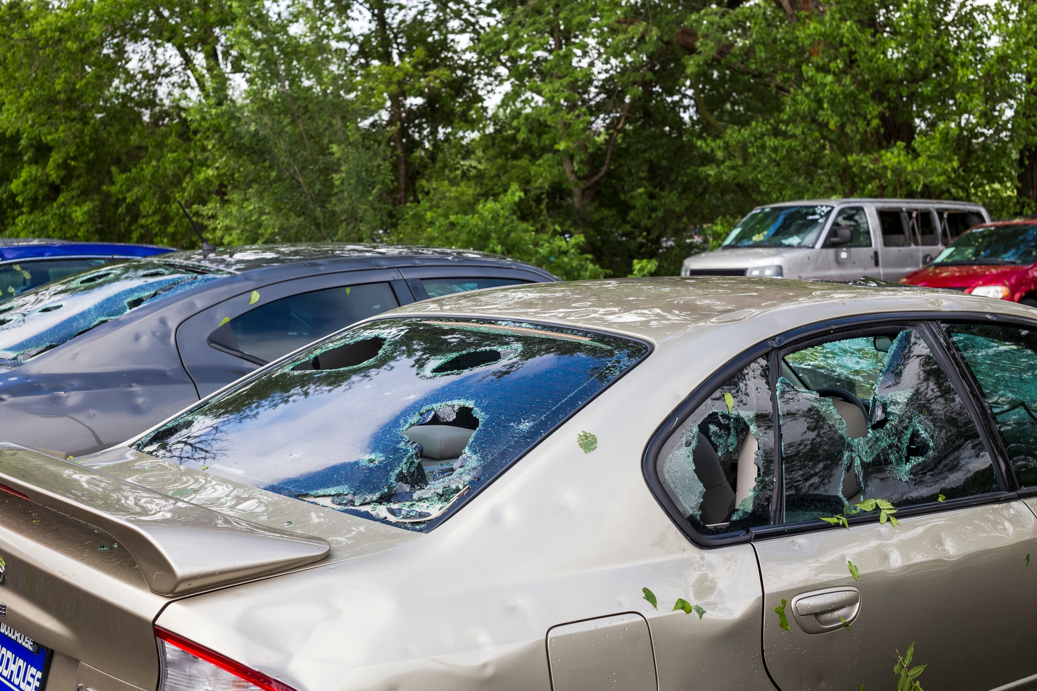 A hail-damaged car with dented body panels and broken windows