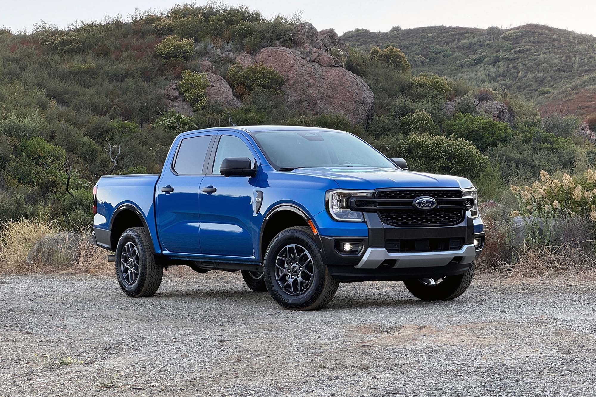 2024 Ford Ranger XLT SuperCrew in Velocity Blue Metallic parked on dirt, front-right view