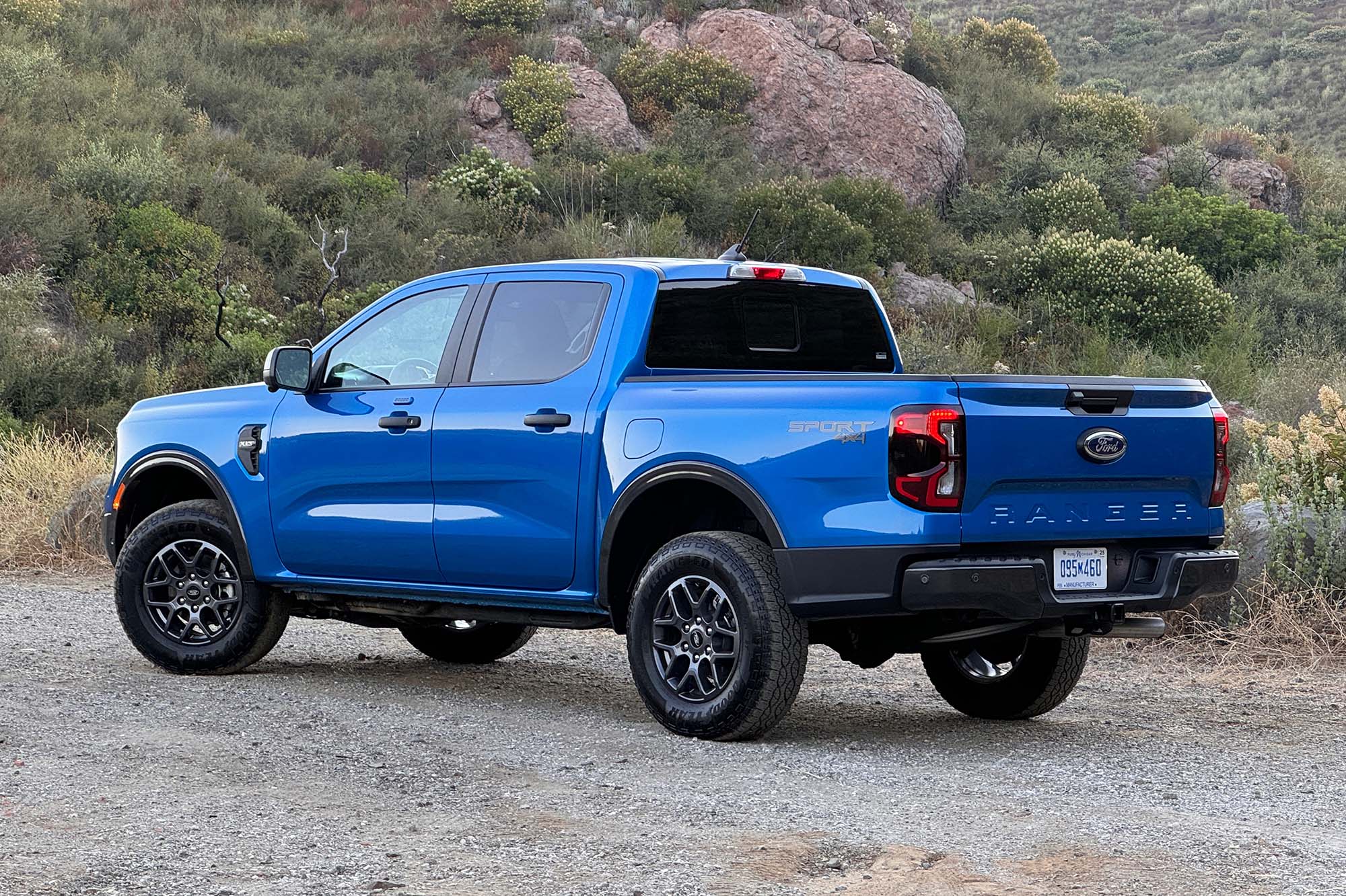 2024 Ford Ranger XLT SuperCrew in Velocity Blue Metallic parked on dirt and gravel, rear