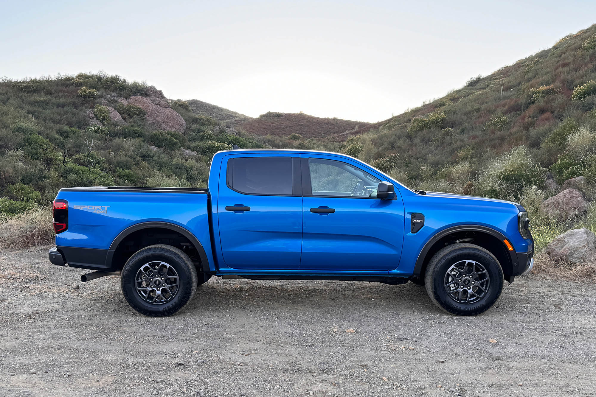 2024 Ford Ranger XLT SuperCrew in Velocity Blue Metallic parked on dirt, side view