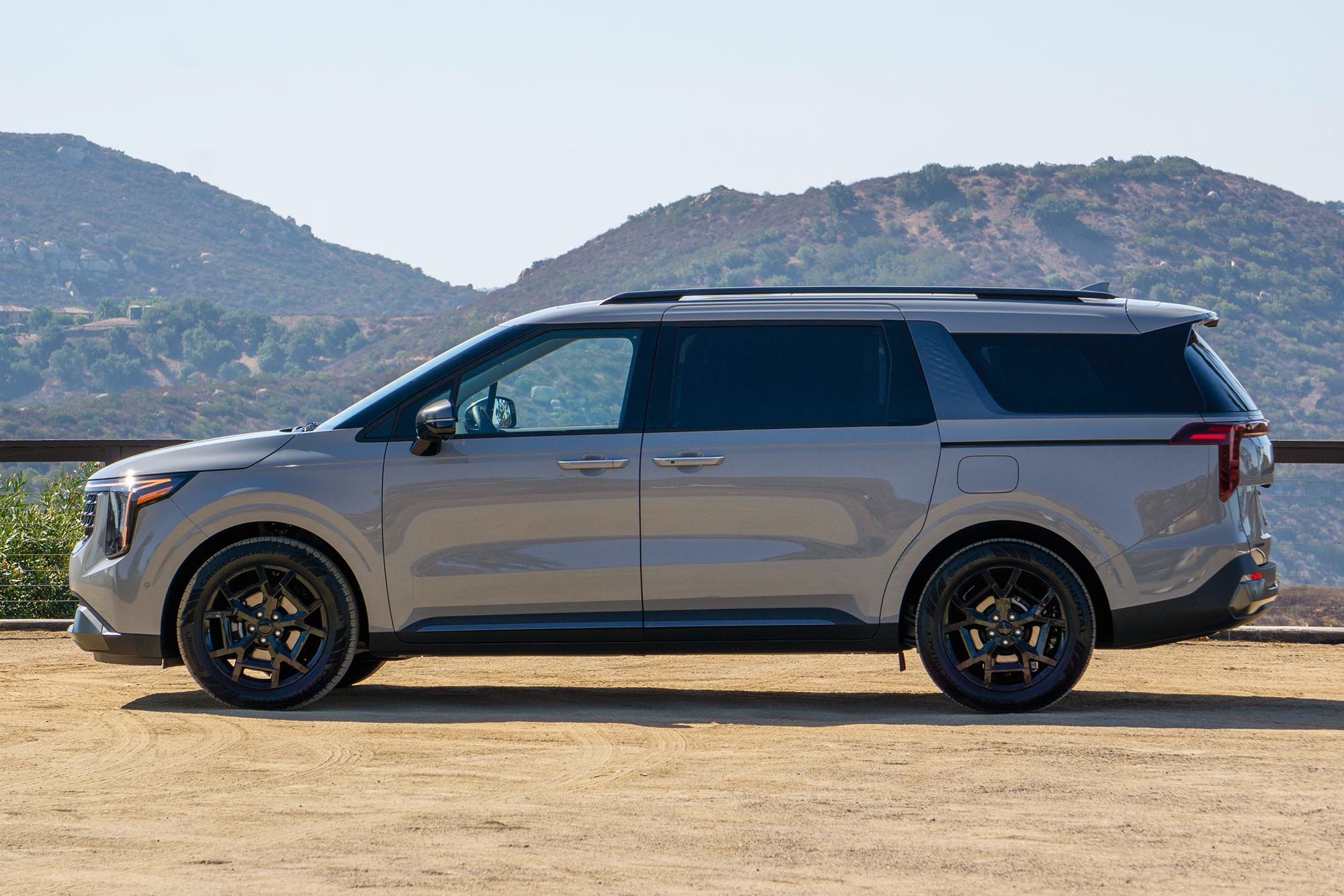 2025 Kia Carnival Hybrid SX Prestige in Ceramic Silver with mountains in the background.