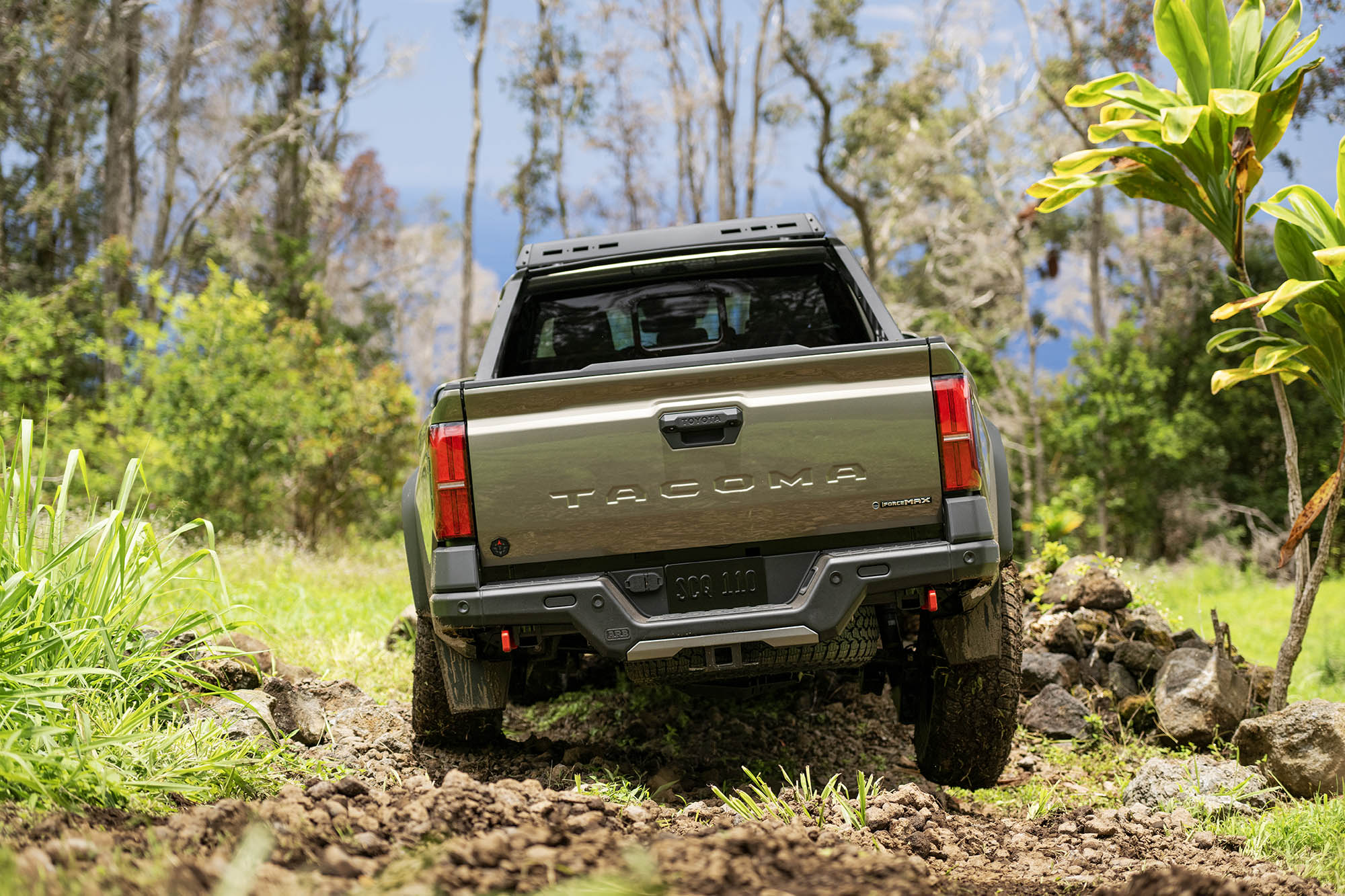 Rear view of a green Toyota Tacoma off-roading