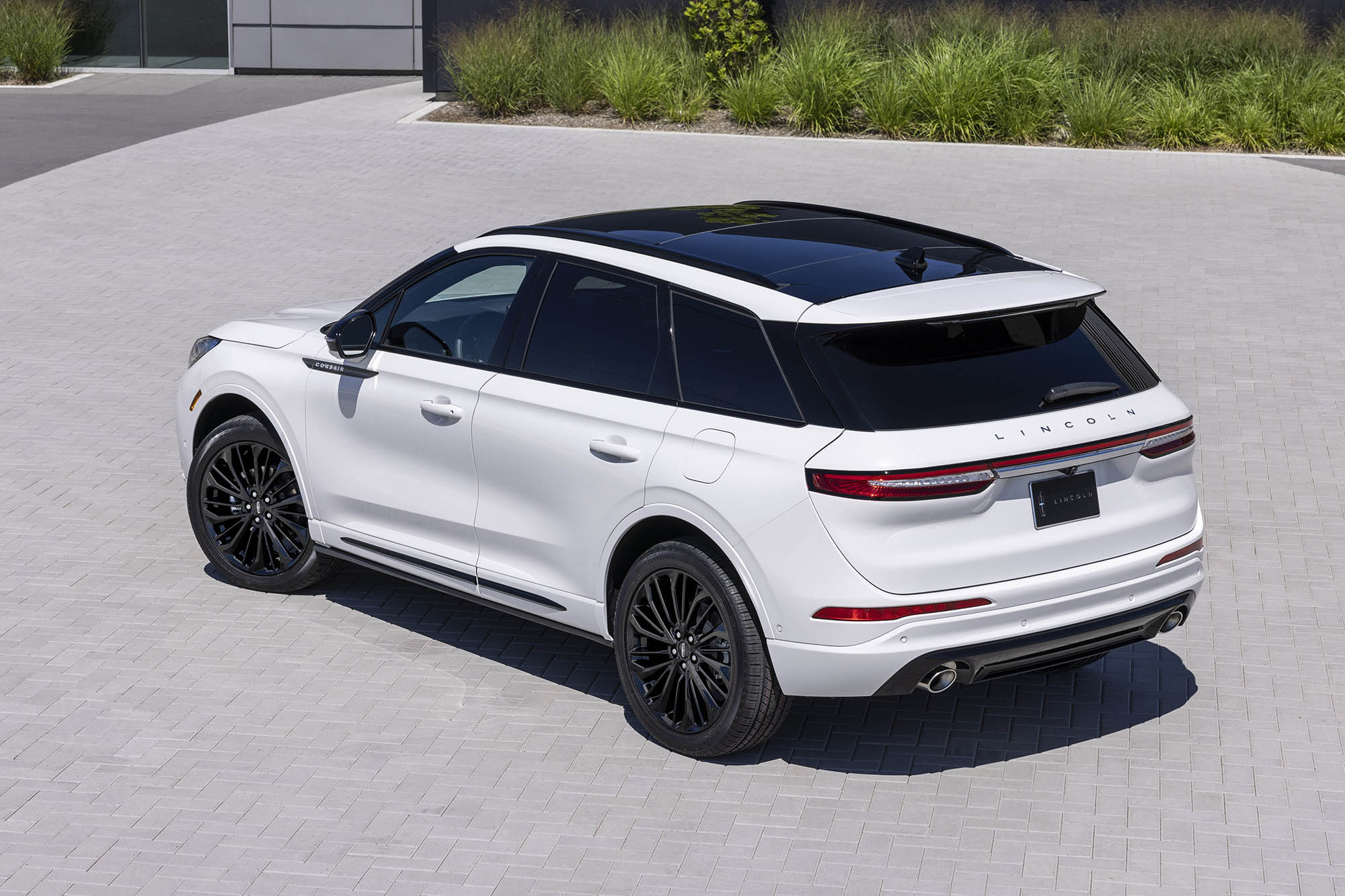 White Lincoln Corsair parked on gray bricks.