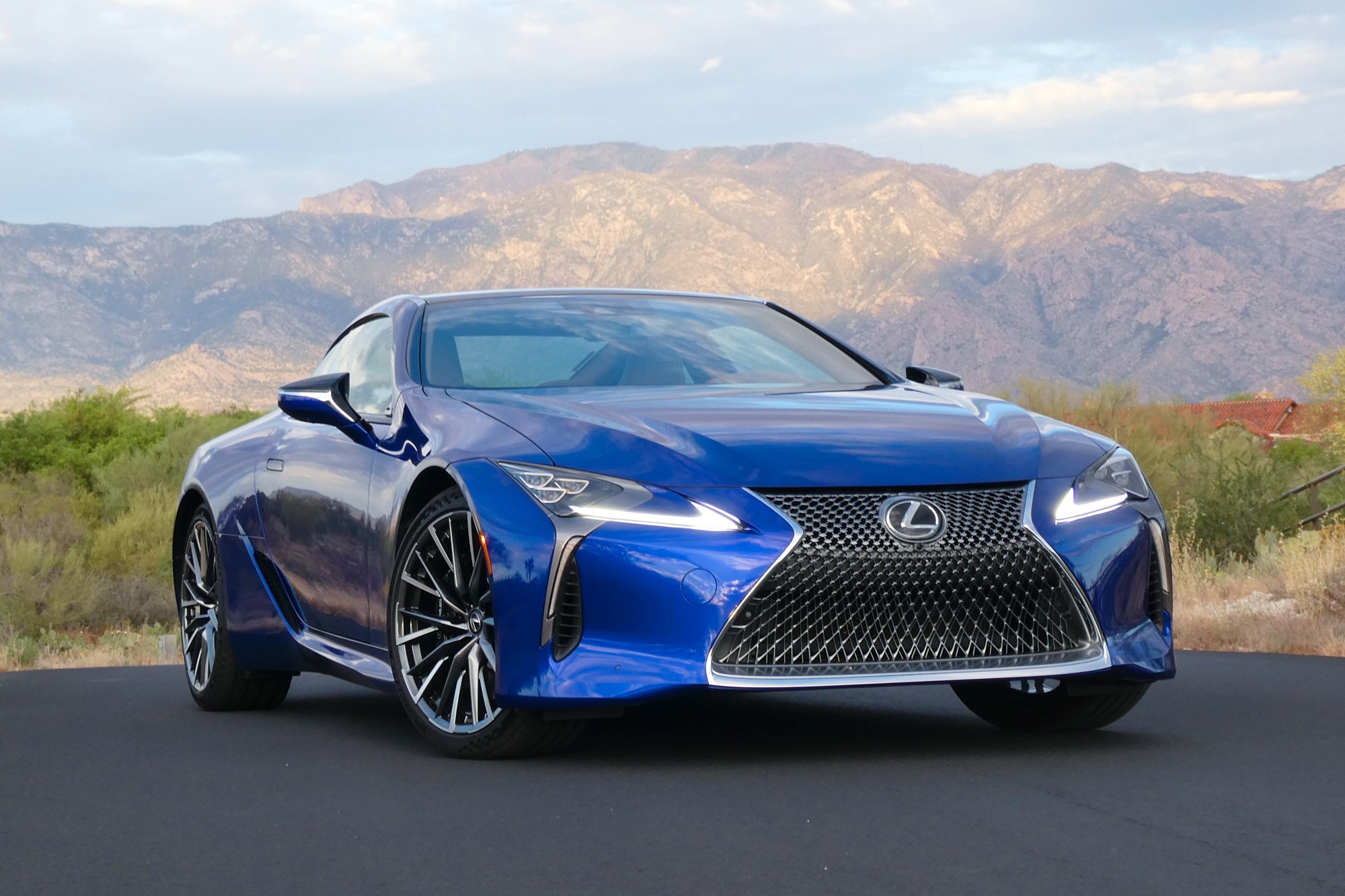 Front-quarter of a blue 2024 Lexus LC 500h with desert and mountains in the background